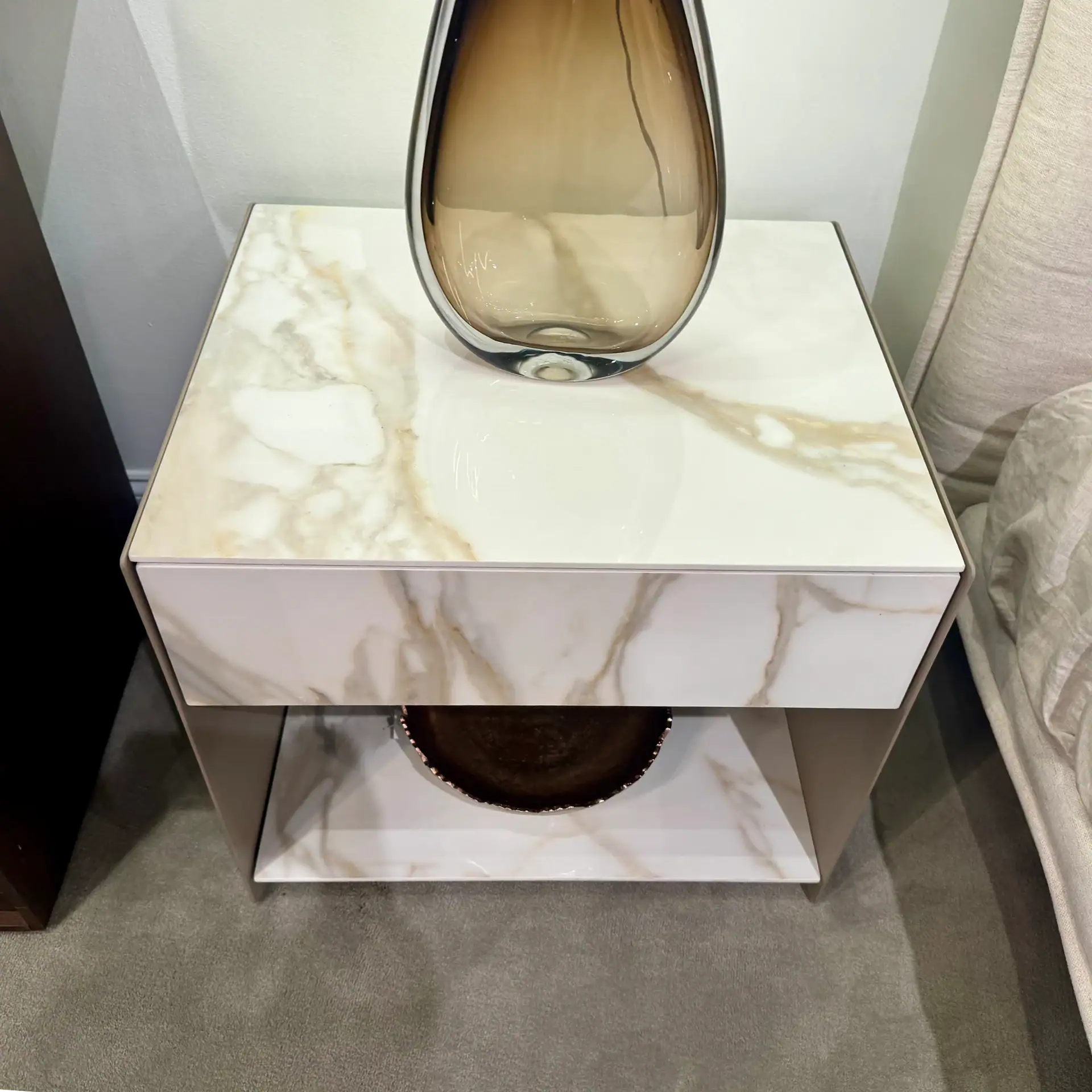 Elegant marble nightstand with a decorative vase on top, modern bedroom furniture.