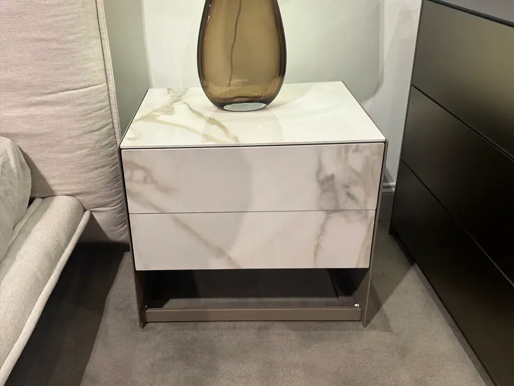 Modern white marble nightstand with black metal base and a decorative vase on top.