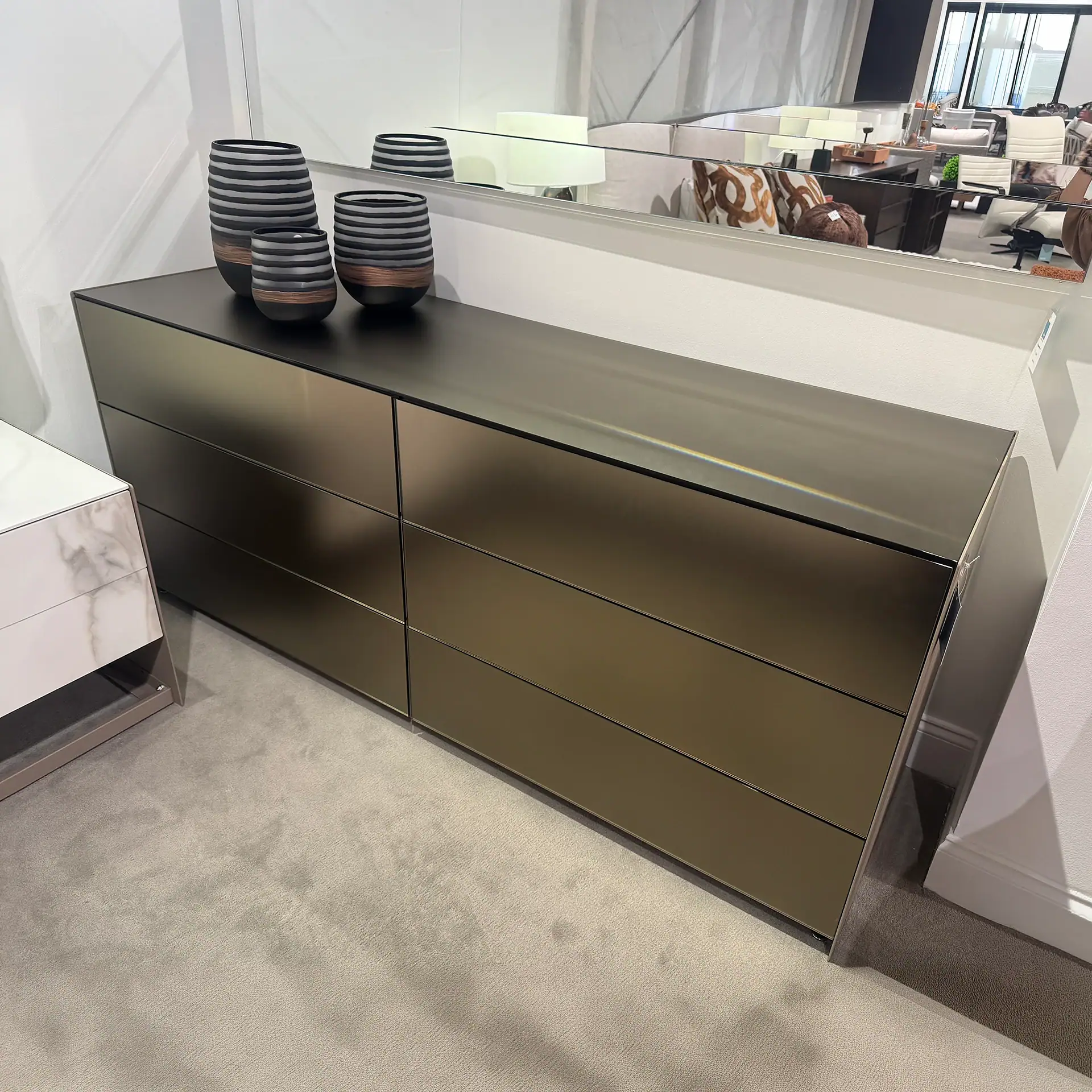 Modern six-drawer dresser with a sleek metallic finish and decorative vases on top.