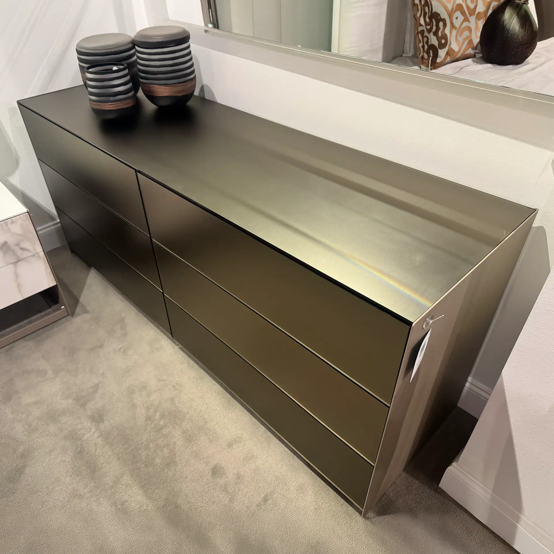 Modern black 6-drawer dresser with decorative vases on top.