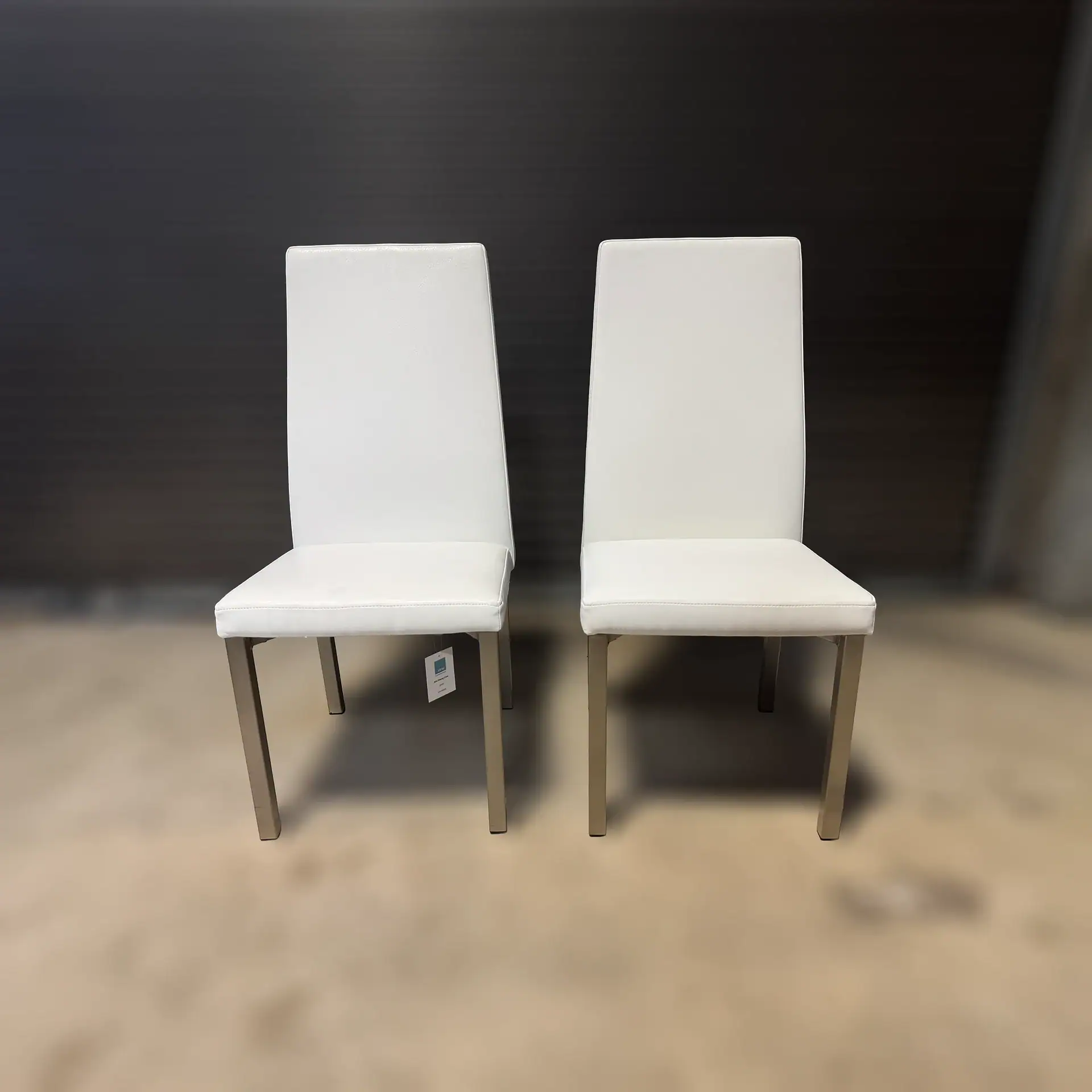 Pair of modern white dining chairs with sleek design and metal legs.