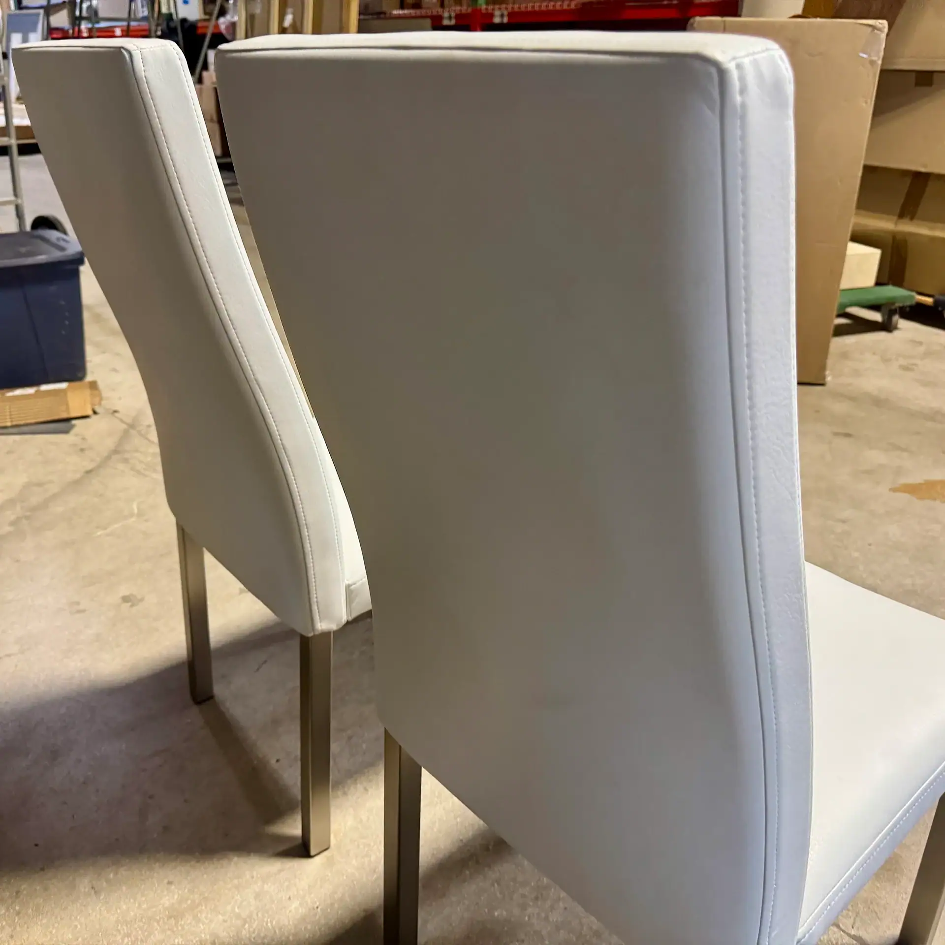 Set of two modern white dining chairs with metal legs.