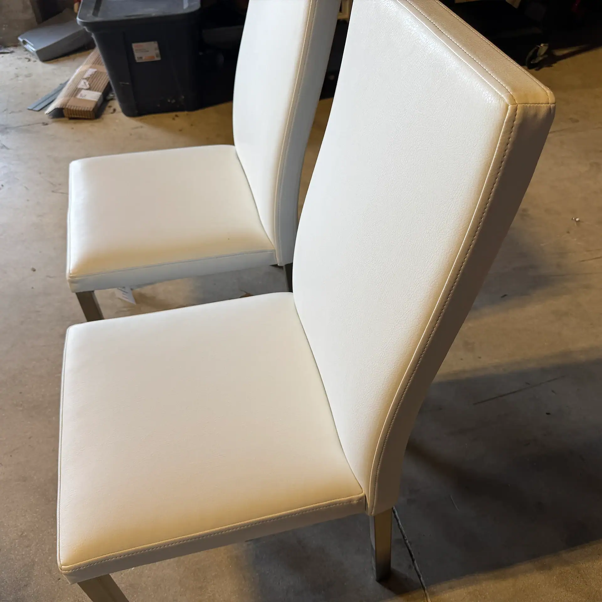 Set of two white upholstered dining chairs with high backs.