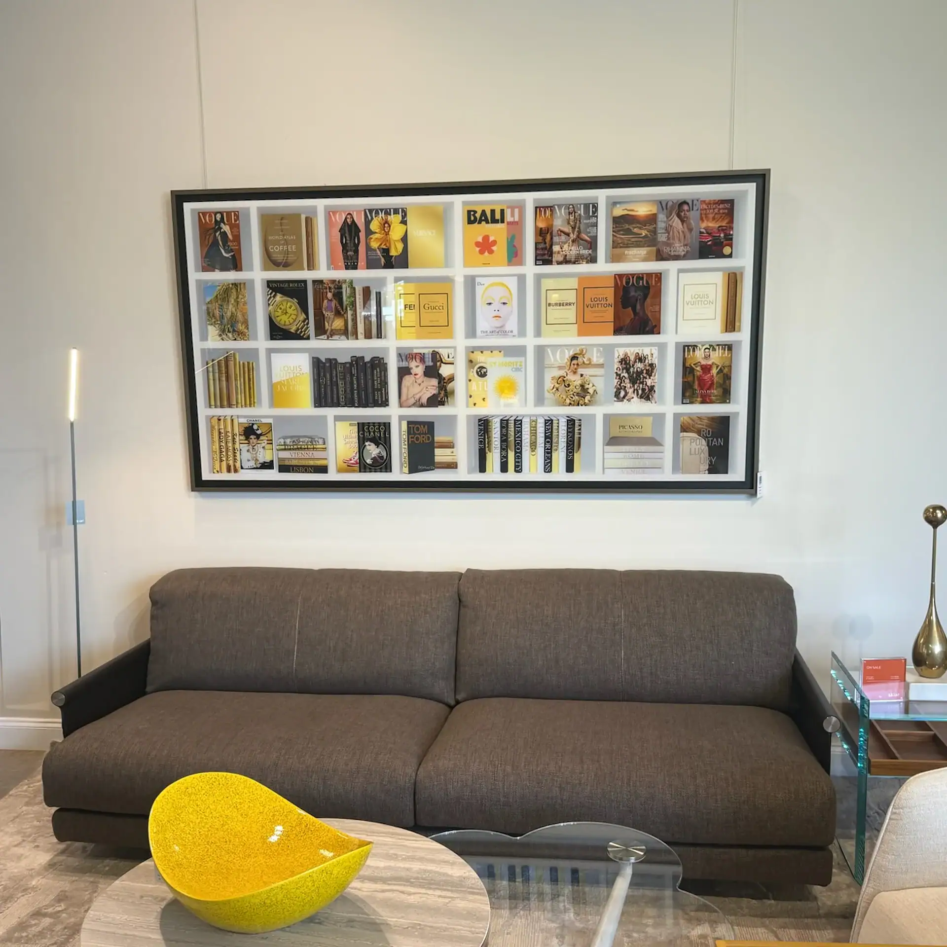 Modern living room with gray sofa and vibrant book display wall.
