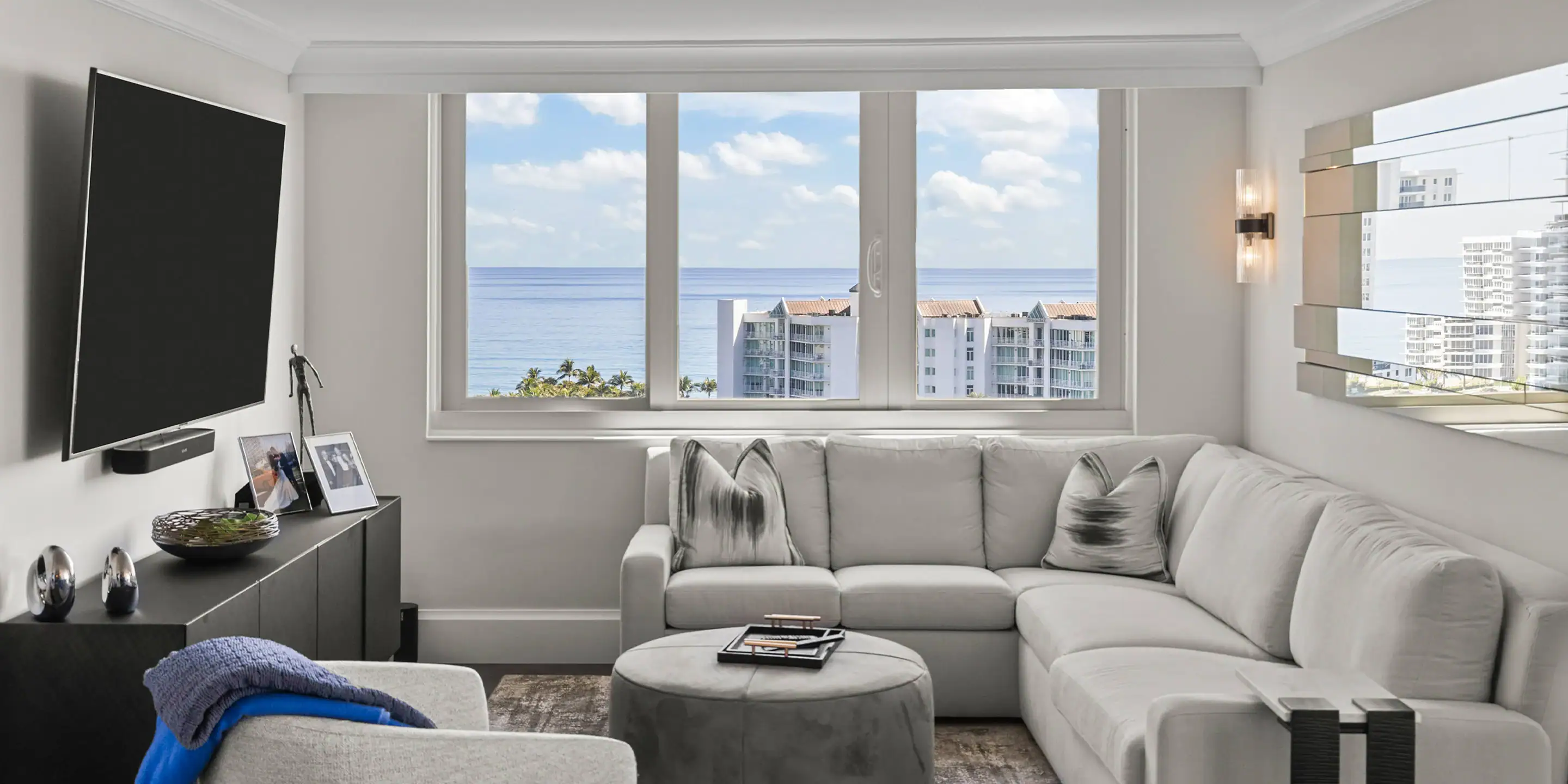 Bright living room with large windows overlooking the ocean, featuring contemporary white sofa and m.