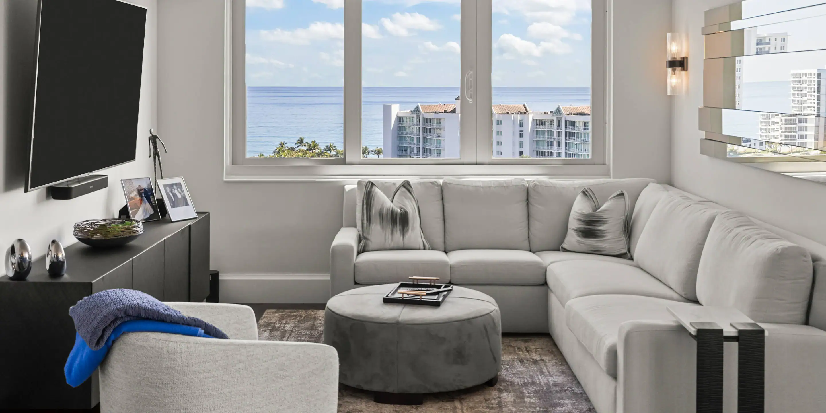 Bright living room with large windows overlooking the ocean, featuring contemporary white sofa and m.