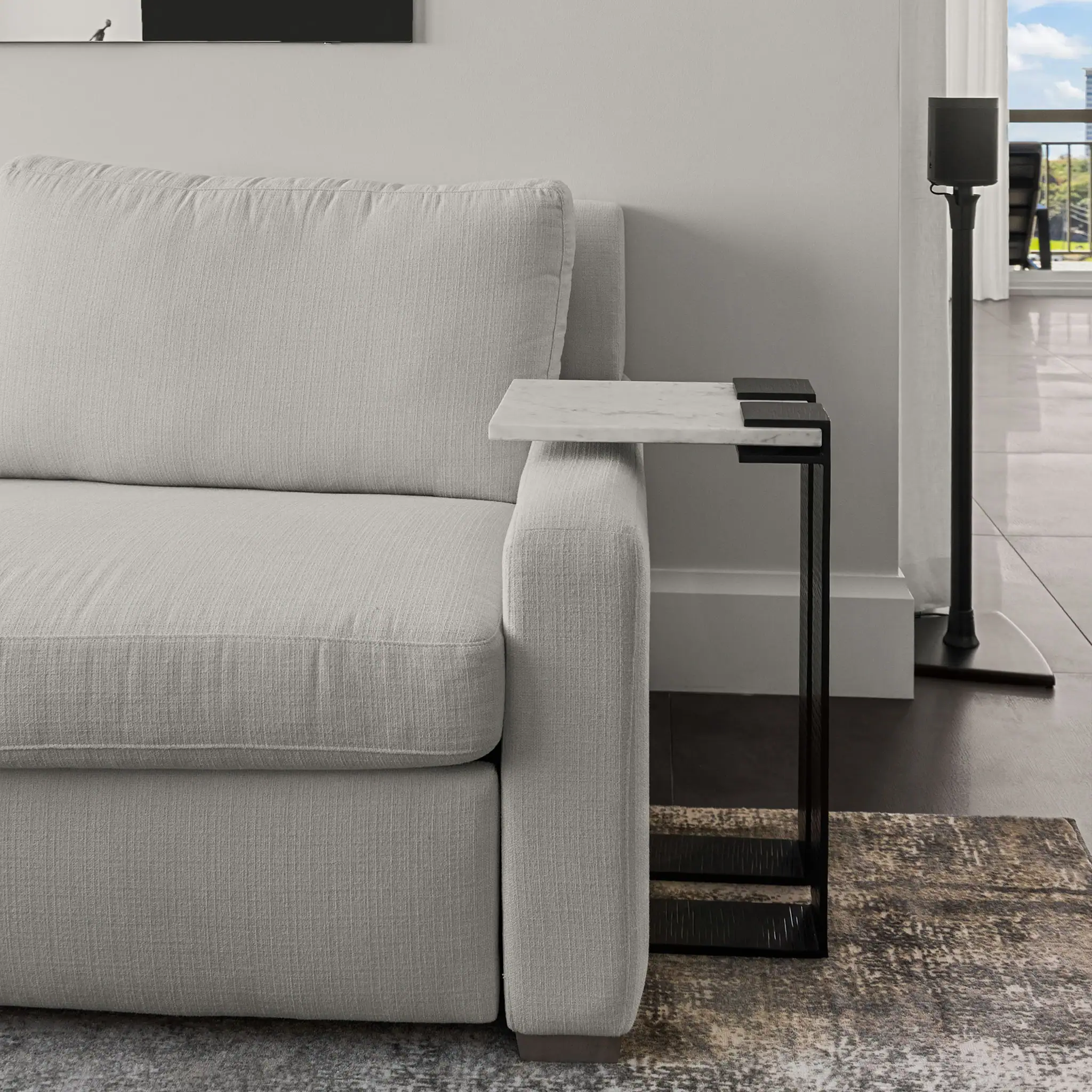 Contemporary light gray sofa with side table and floor lamp in stylish living room.
