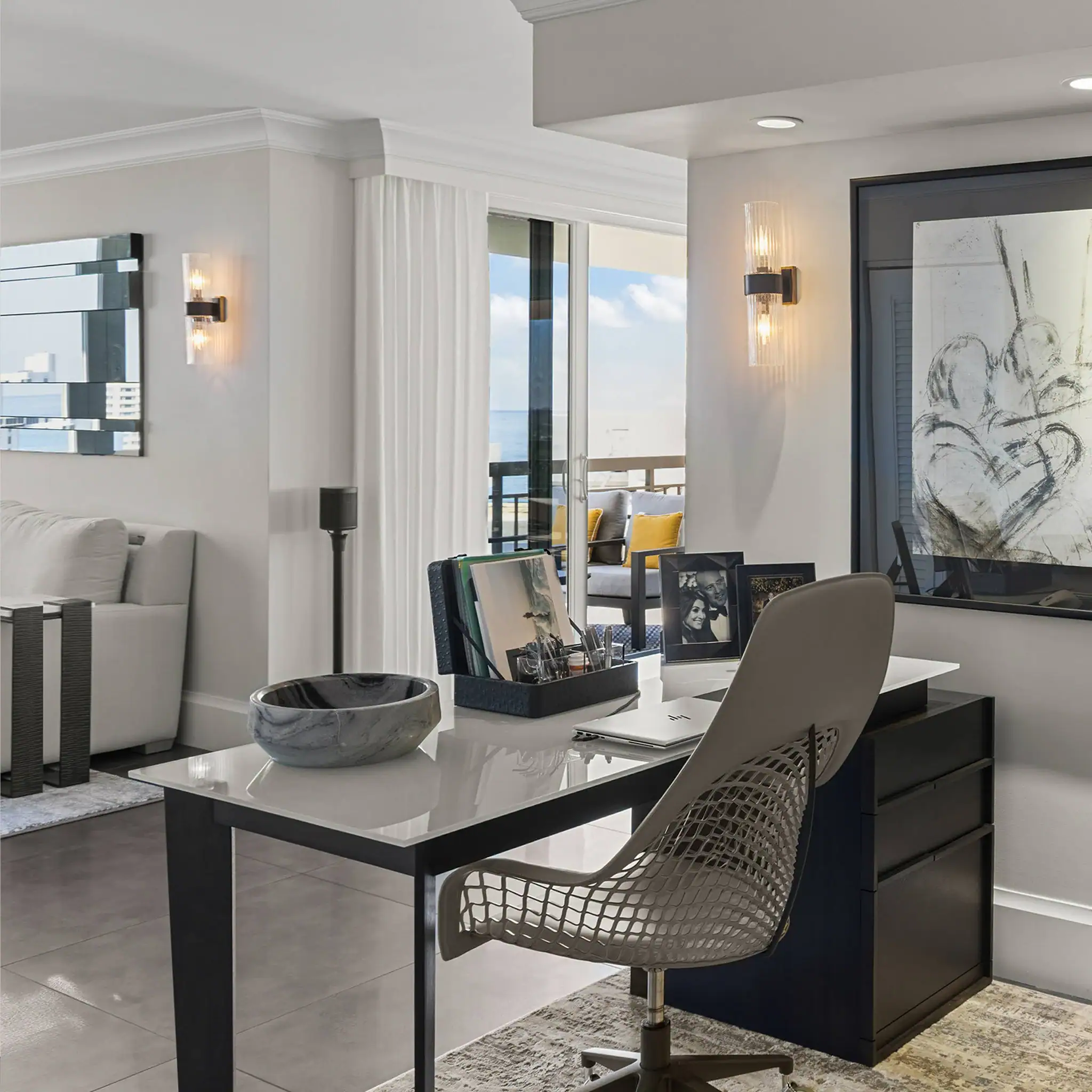 Contemporary living room with workspace and balcony view, stylish decor, and natural light.
