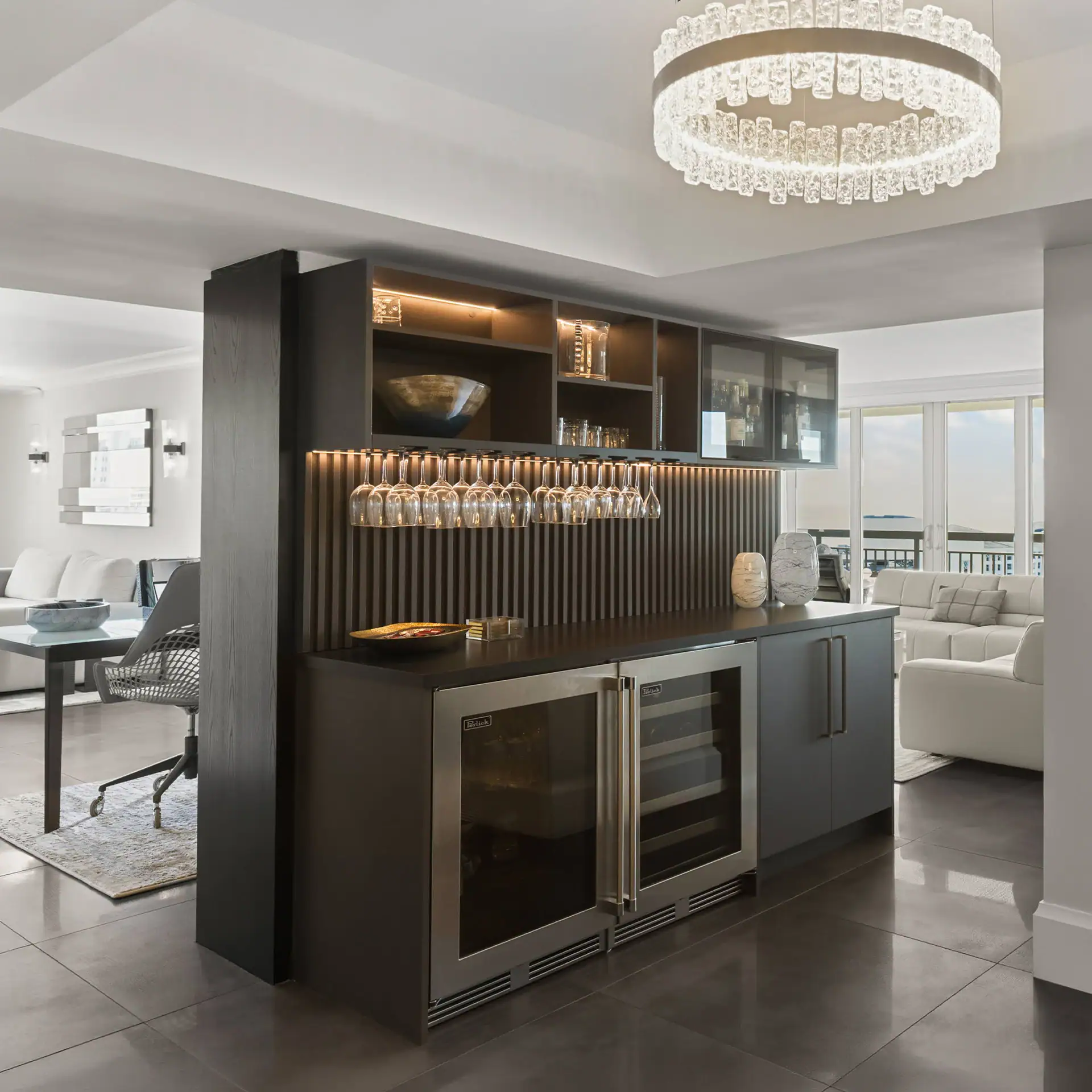 Contemporary home bar with wine fridge and glassware display in a stylish living space.