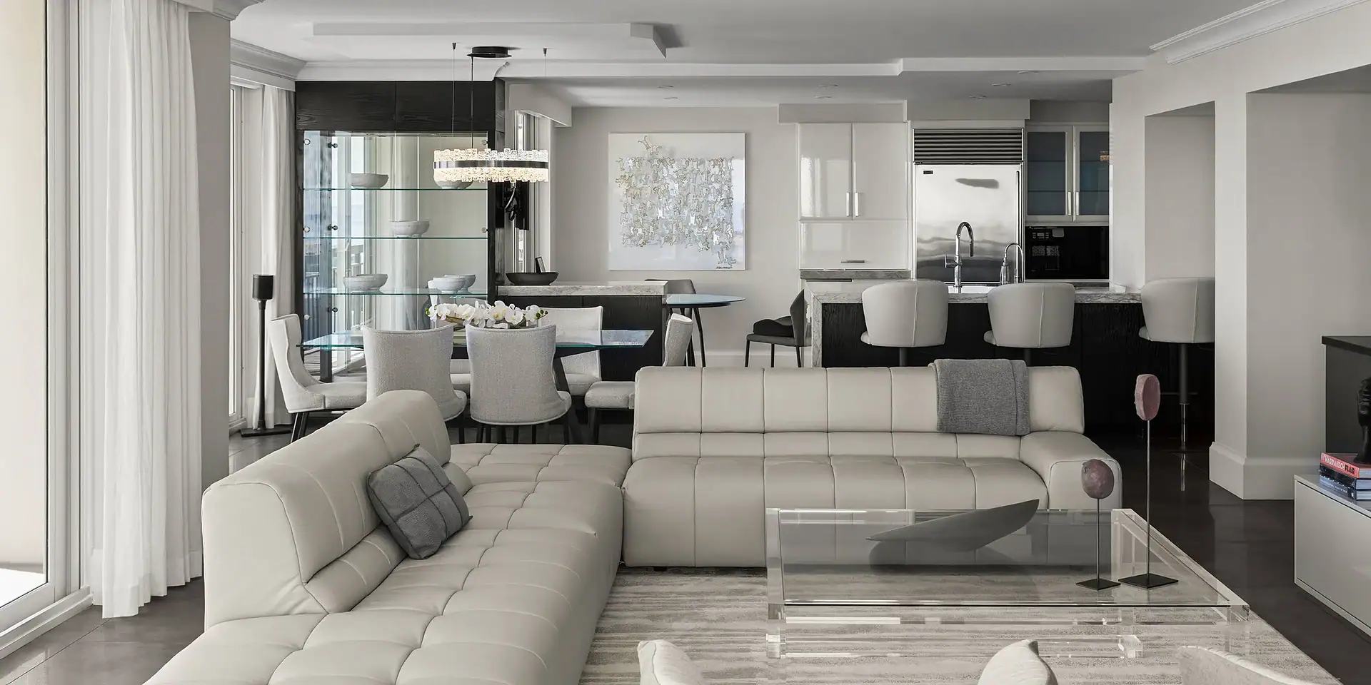 Modern white living room with open kitchen and dining space, featuring contemporary furniture and st.