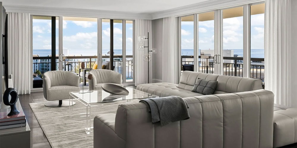 Ocean view living room with contemporary white leather sofas and large glass doors.