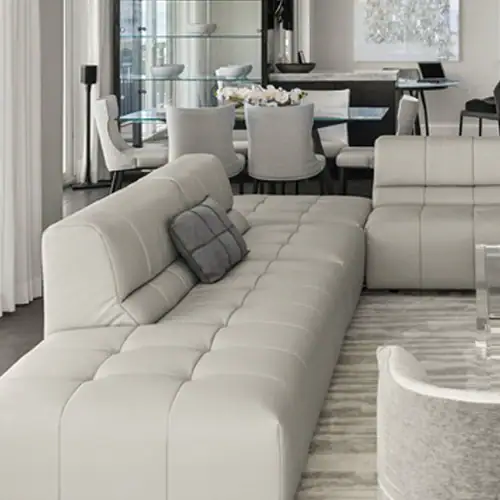 Modern white leather sectional sofa with tufted design and grey accent pillow in contemporary living.