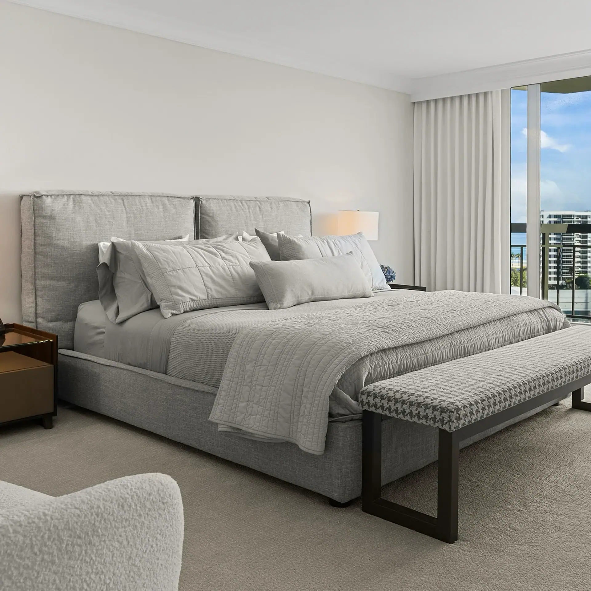 Elegant gray bedroom with large window, city view, and contemporary furnishings.