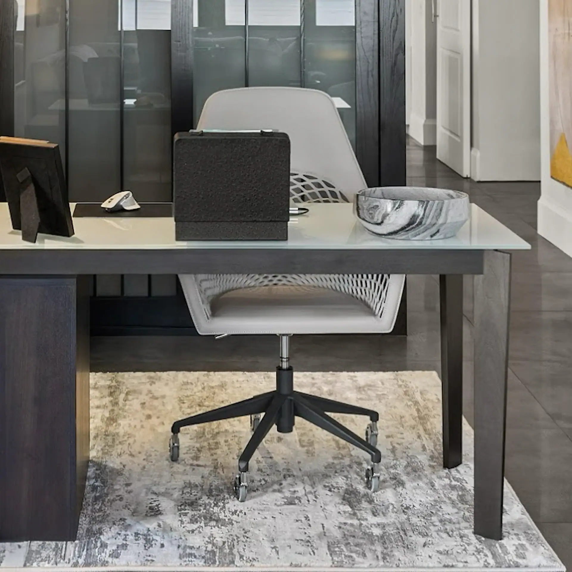 Office desk with ergonomic chair, marble tray, and decorative items in a contemporary workspace.