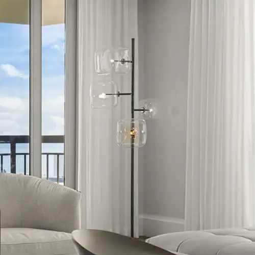 Modern glass pendant floor lamp in a stylish living room with large windows and white curtains.