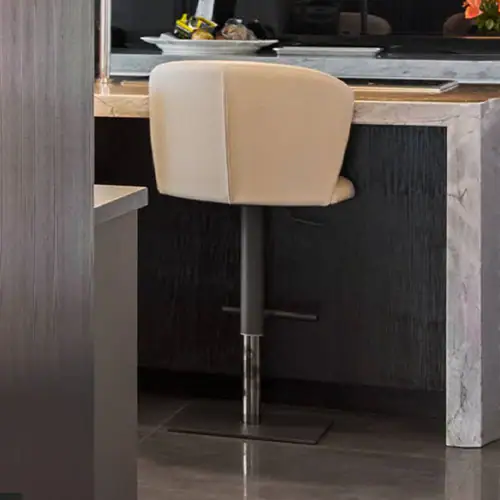 Bar stool with beige upholstered seat and chrome base at kitchen island.