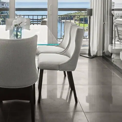 Elegant dining room with contemporary chairs and a scenic ocean view backdrop.