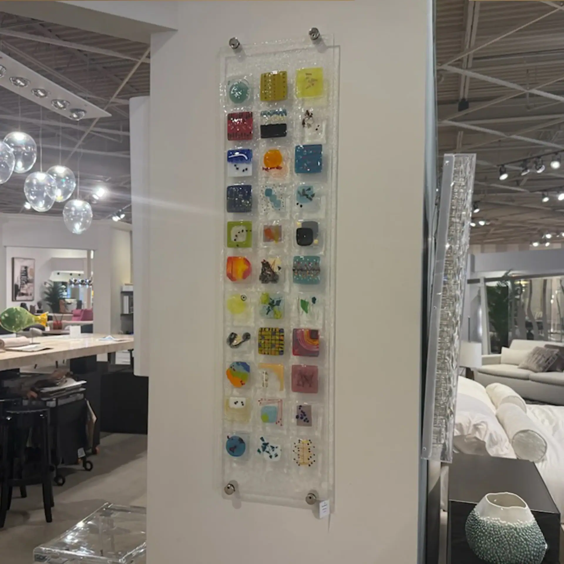 Colorful fused glass wall art display at Sklar Furnishings showroom.