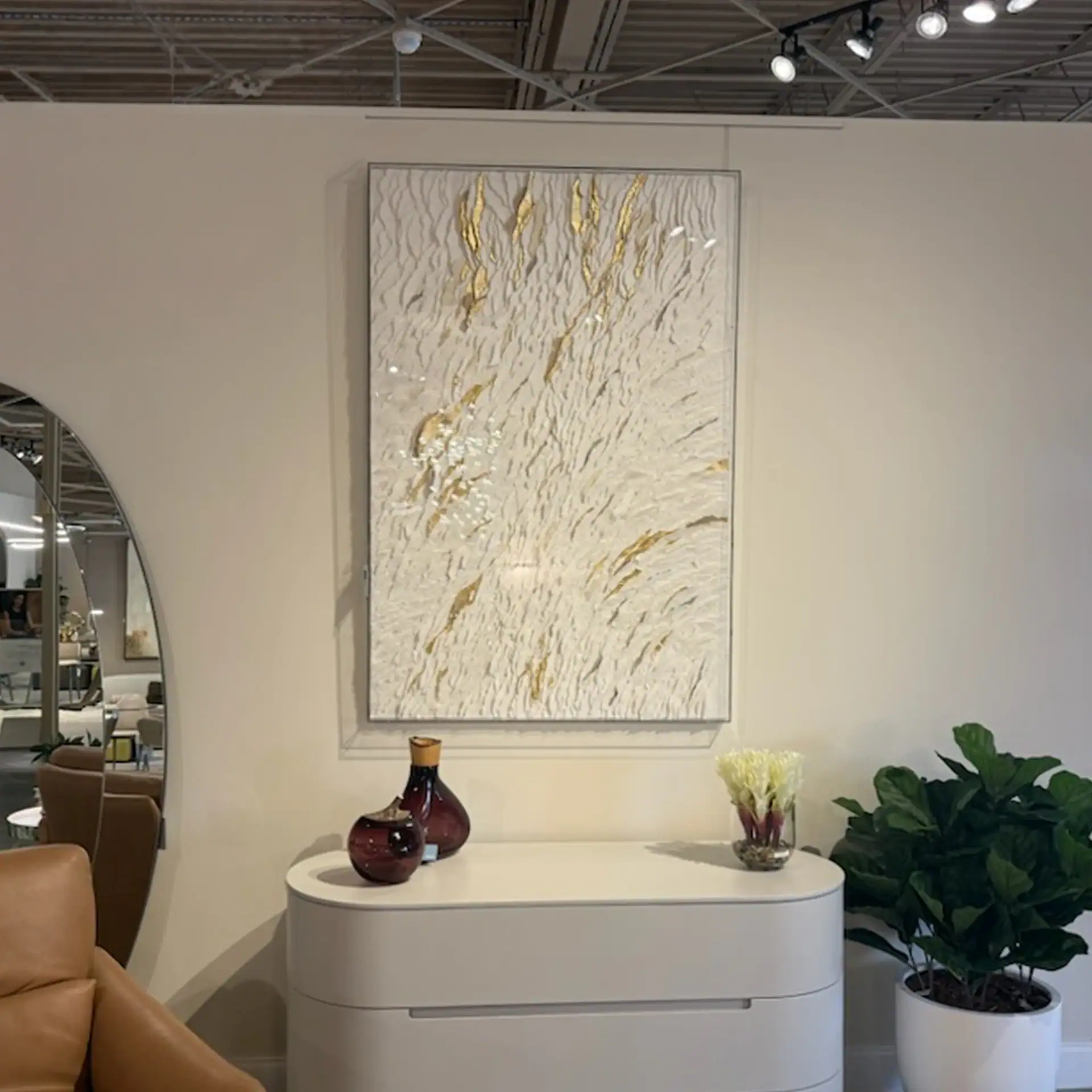 Contemporary home decor featuring textured wall art, vases, and lush green plant.