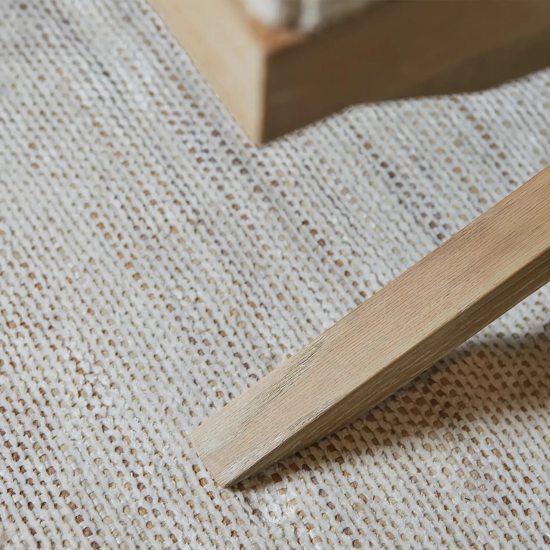 Close-up of textured area rug with wooden furniture leg.