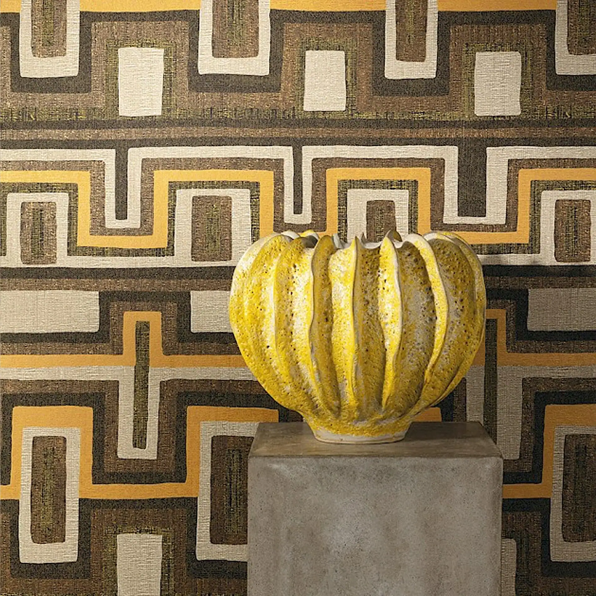 Decorative vase on pedestal in front of geometric patterned wallpaper.