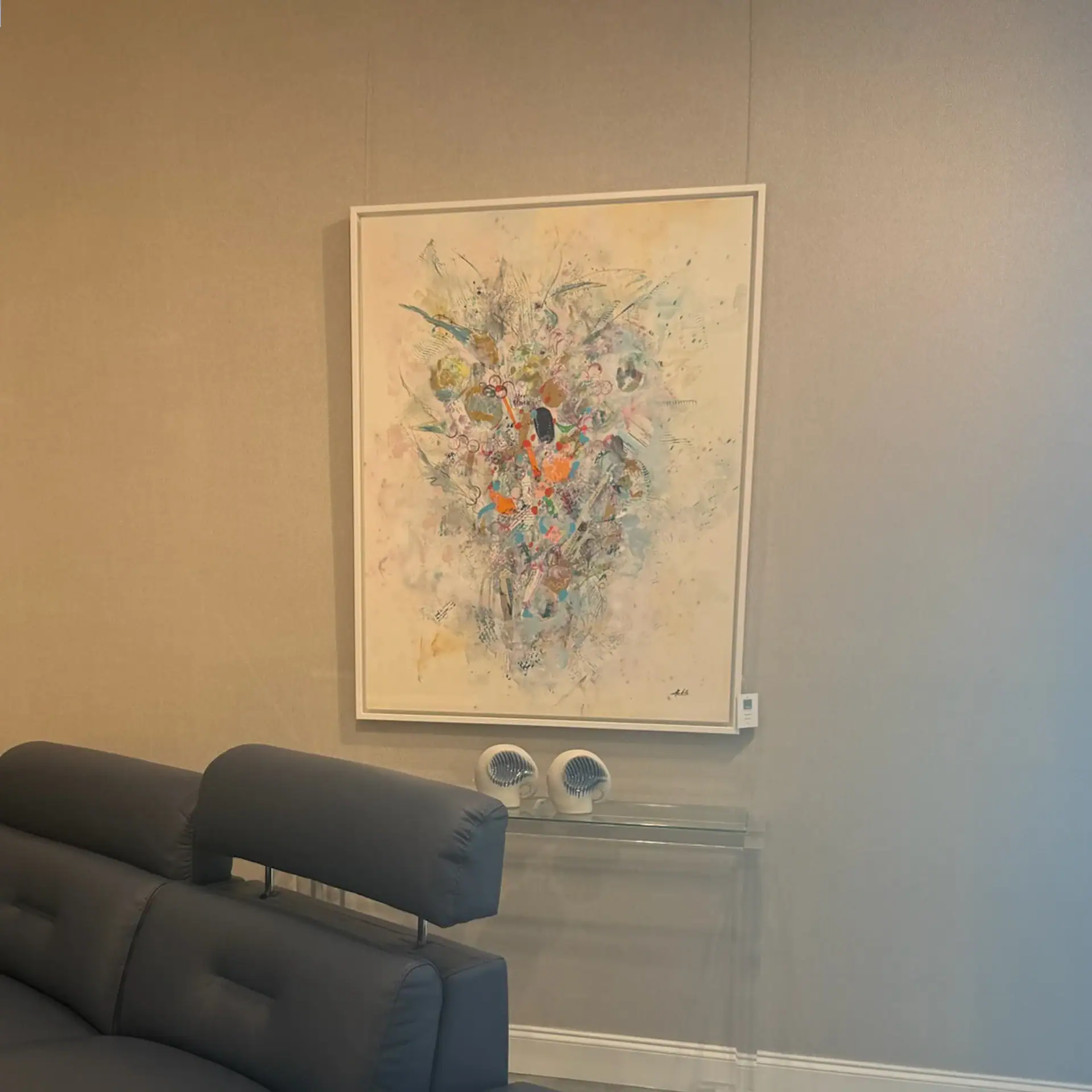 Abstract colorful canvas painting hanging on a wall in a modern living room.