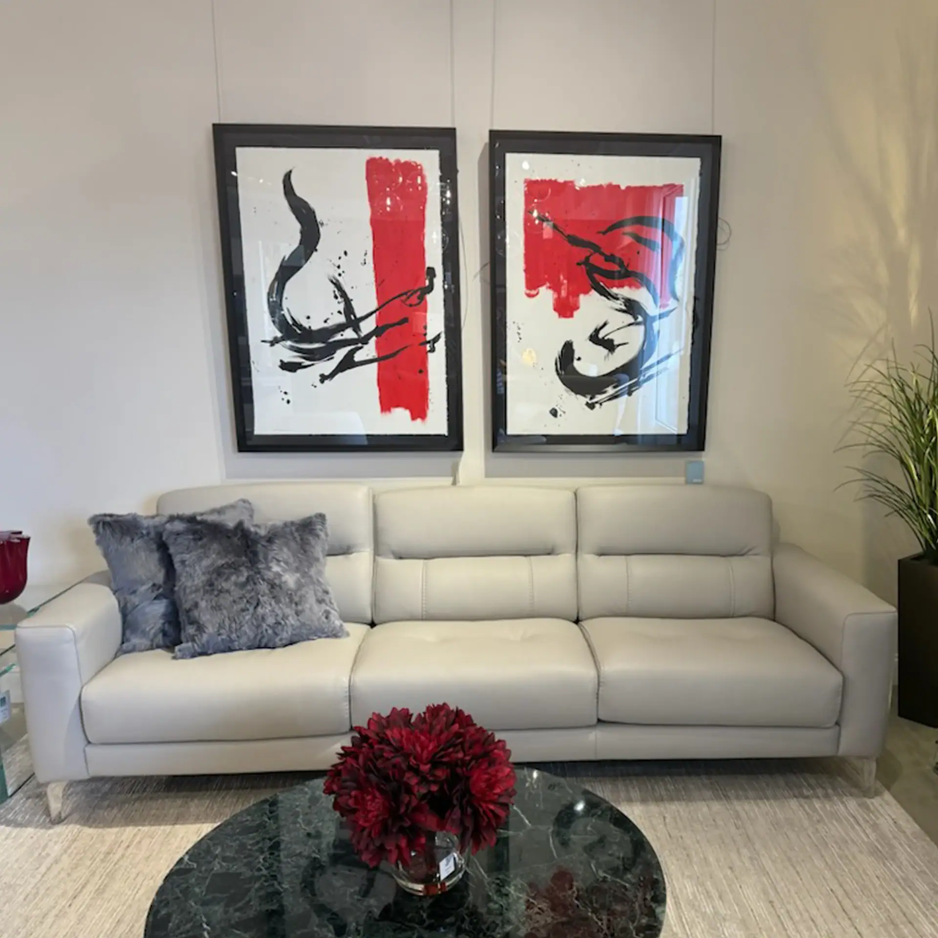 Elegant white leather sofa with abstract art and plush pillows in a stylish living space.