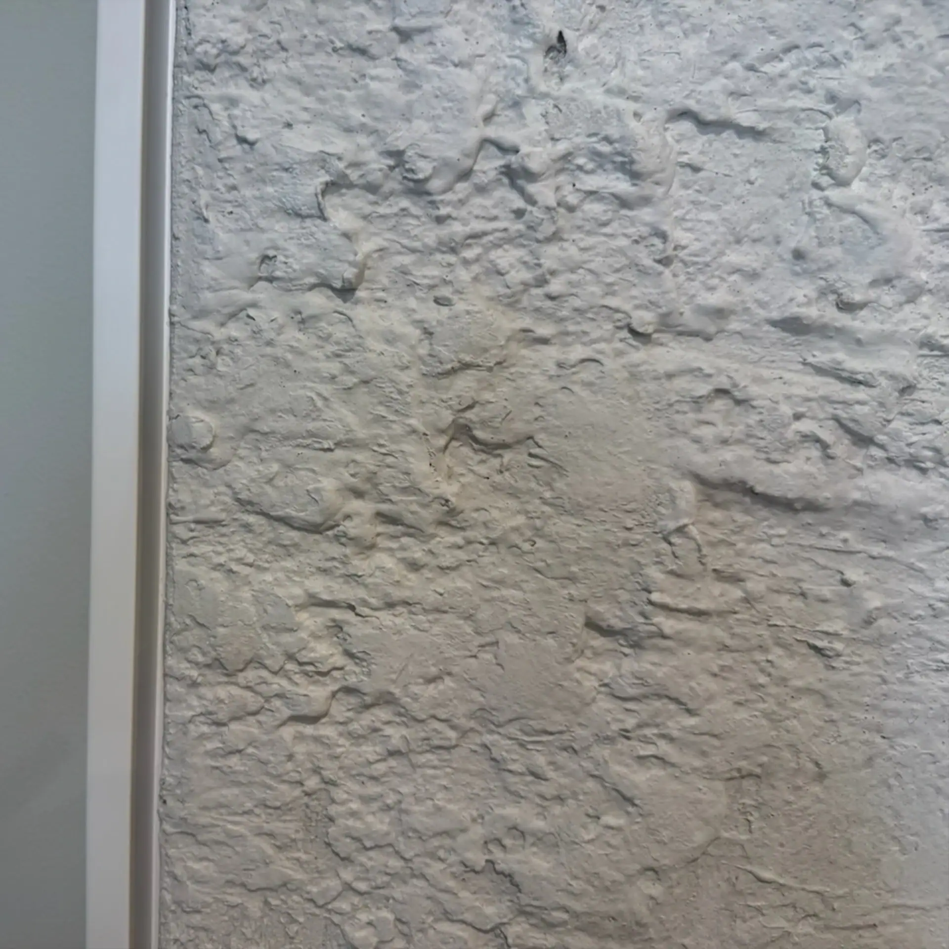 Close-up of a textured white wall with rough surface details.