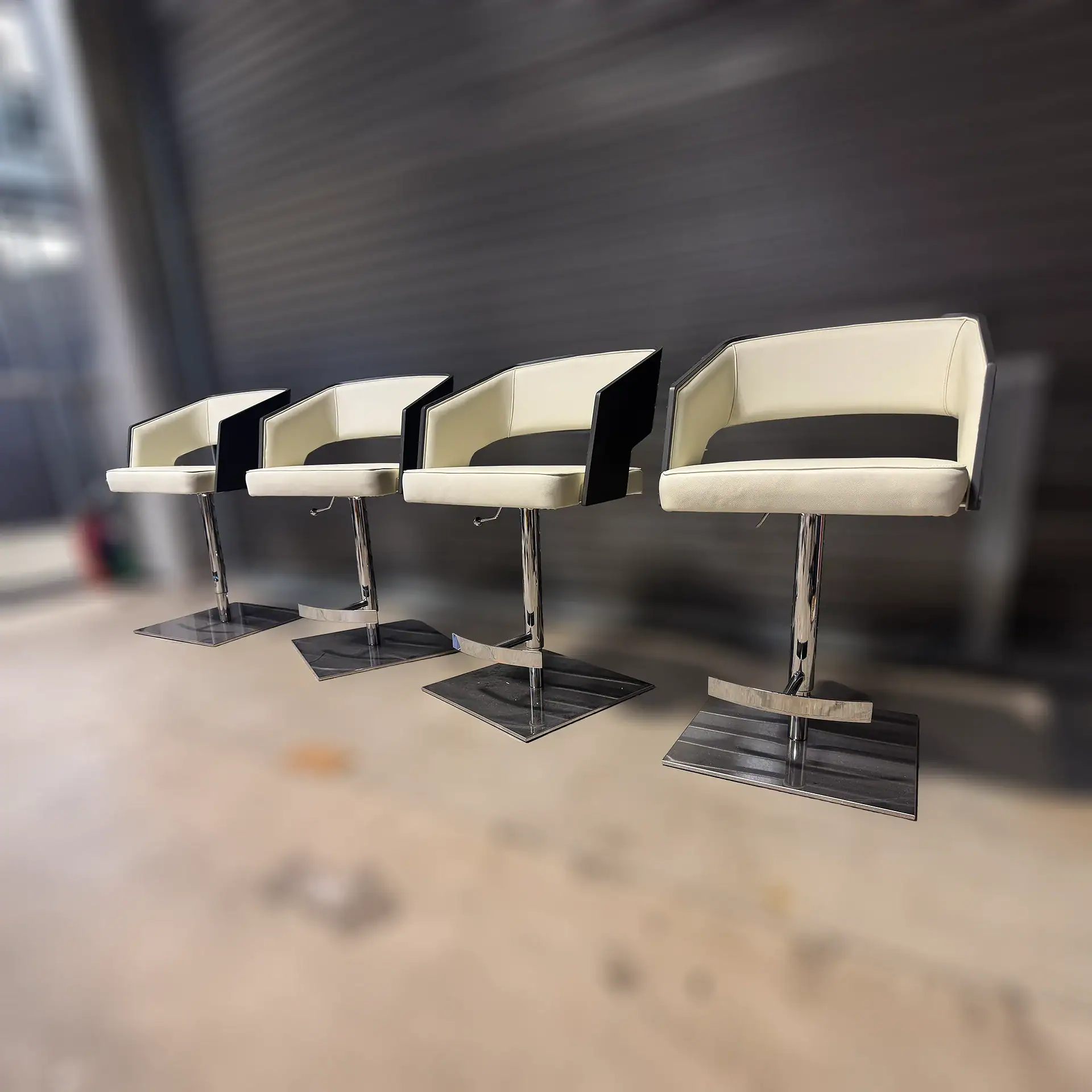 Set of four modern adjustable barstools with cream and black upholstery.