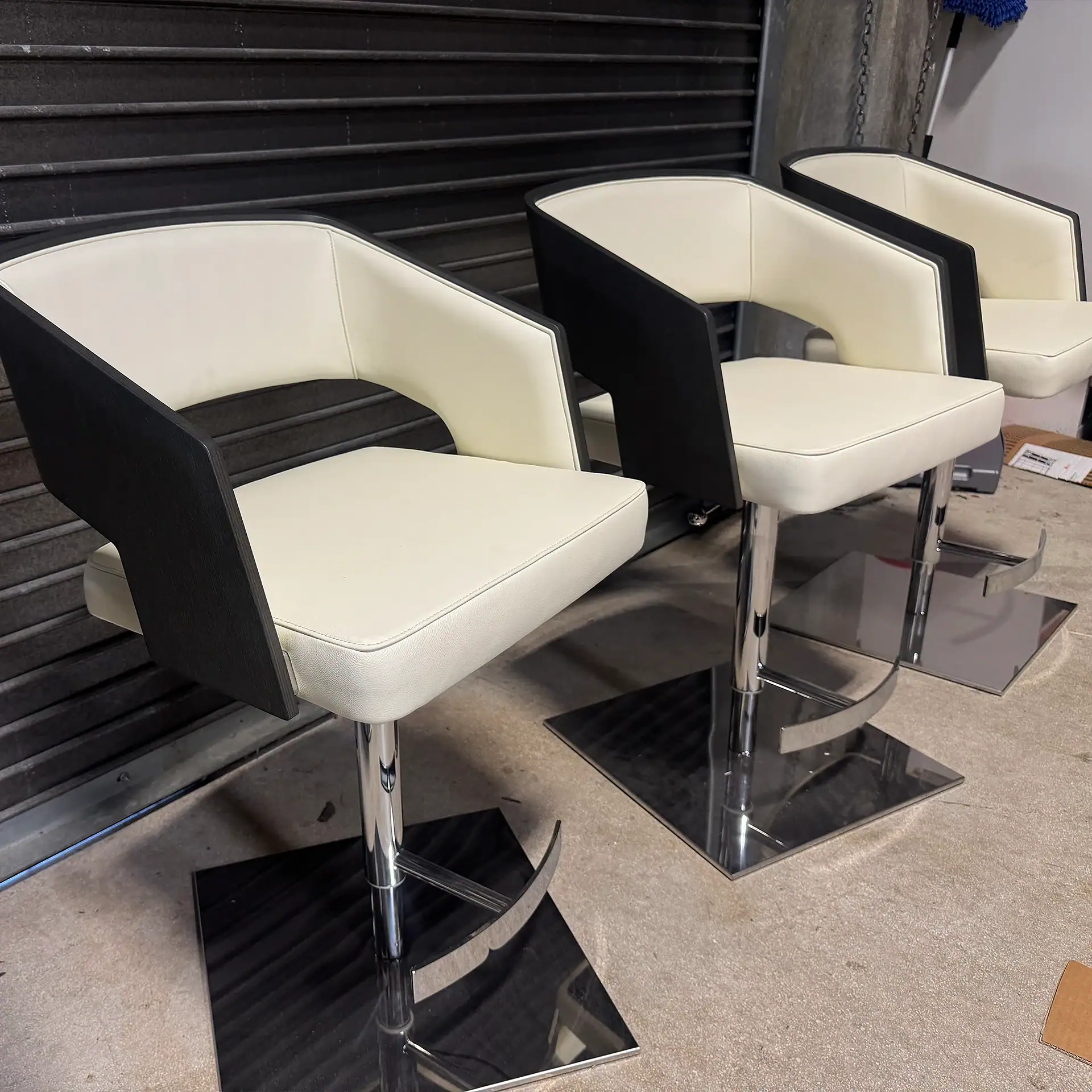 Set of three modern black and white barstools with chrome bases.
