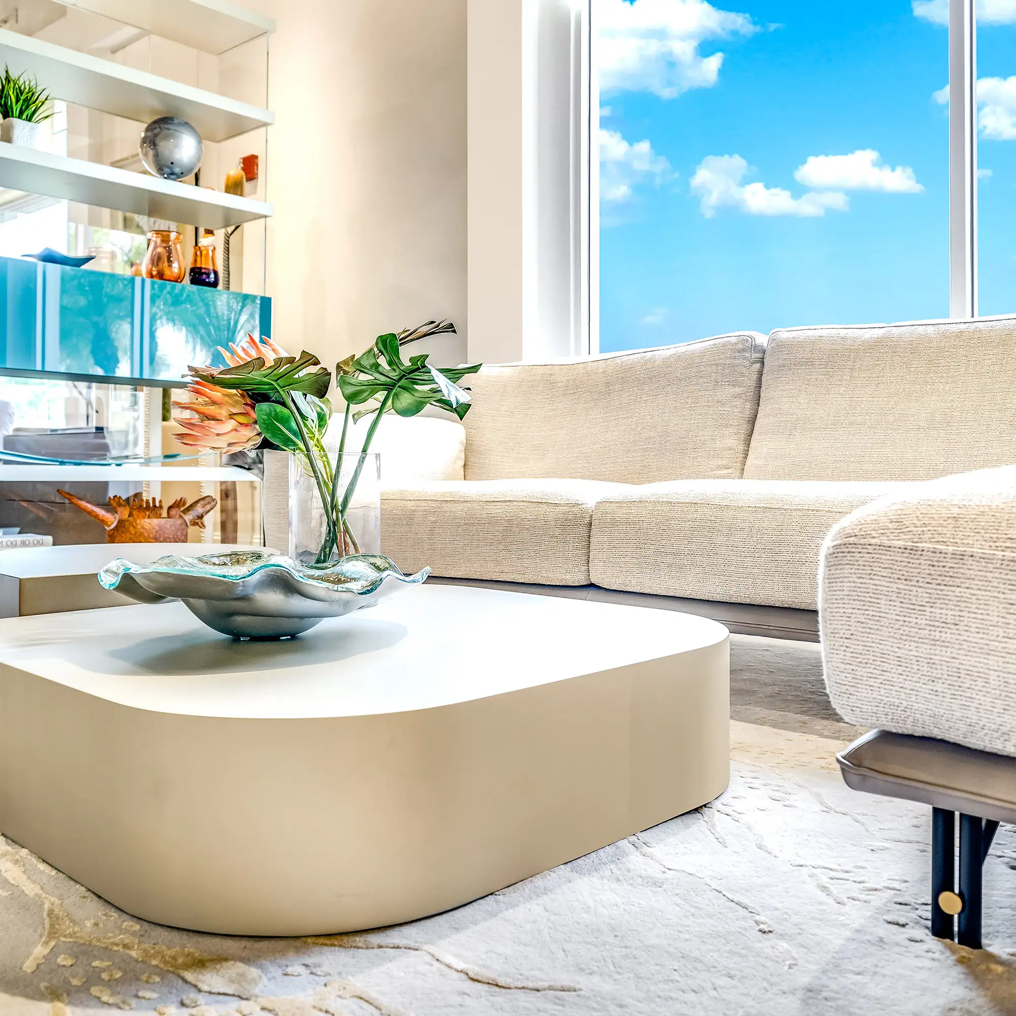 Modern Living Room with Natural Light Bright living room with beige sofa and large window showing blue sky.