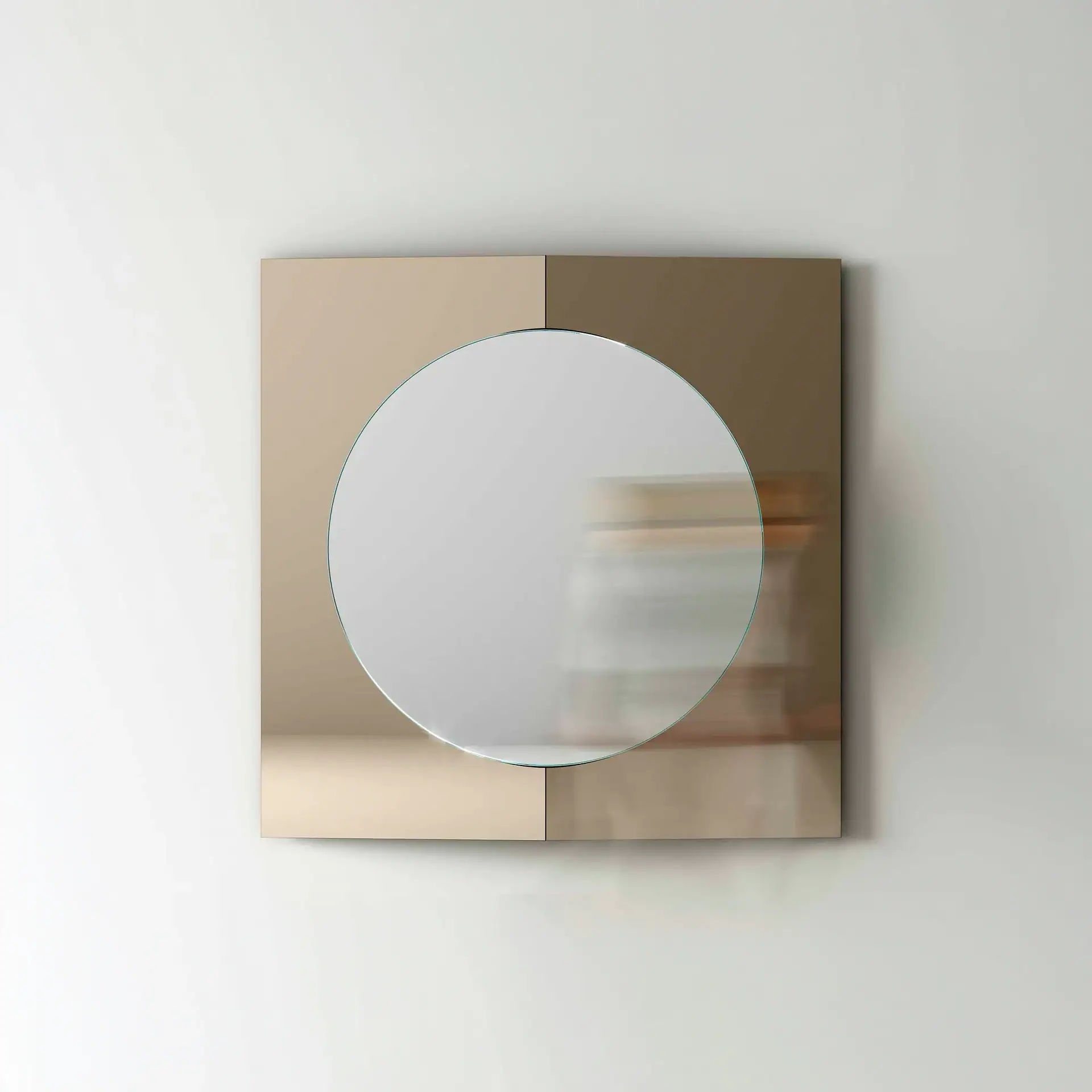 A square mirror with a circular mirror inset, featuring a two-tone reflective frame in beige-gold and bronze-brown, mounted on a white wall.