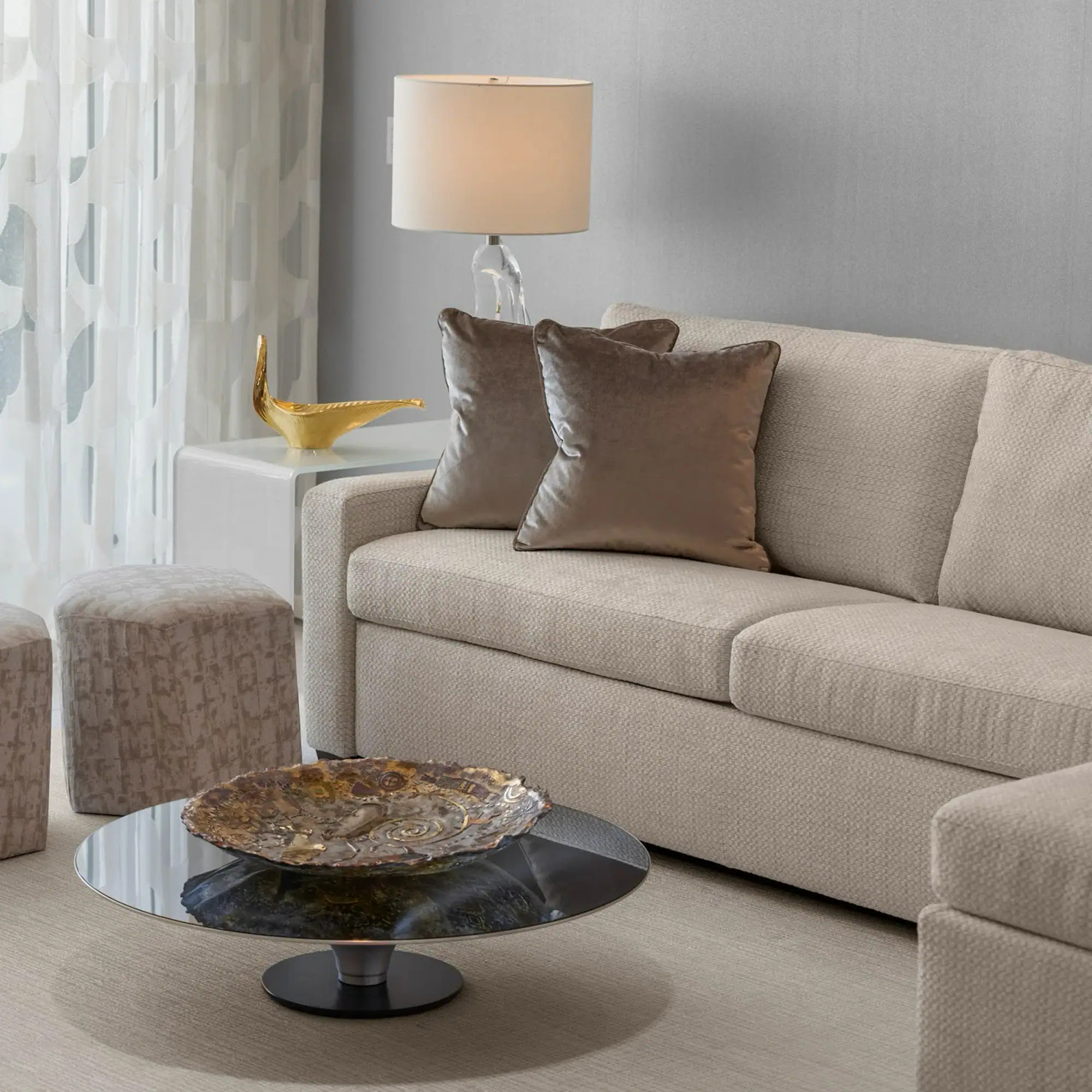 Contemporary Living Room Sofa Setup Neutral beige sofa with metallic pillows and a round coffee table in a modern living room.
