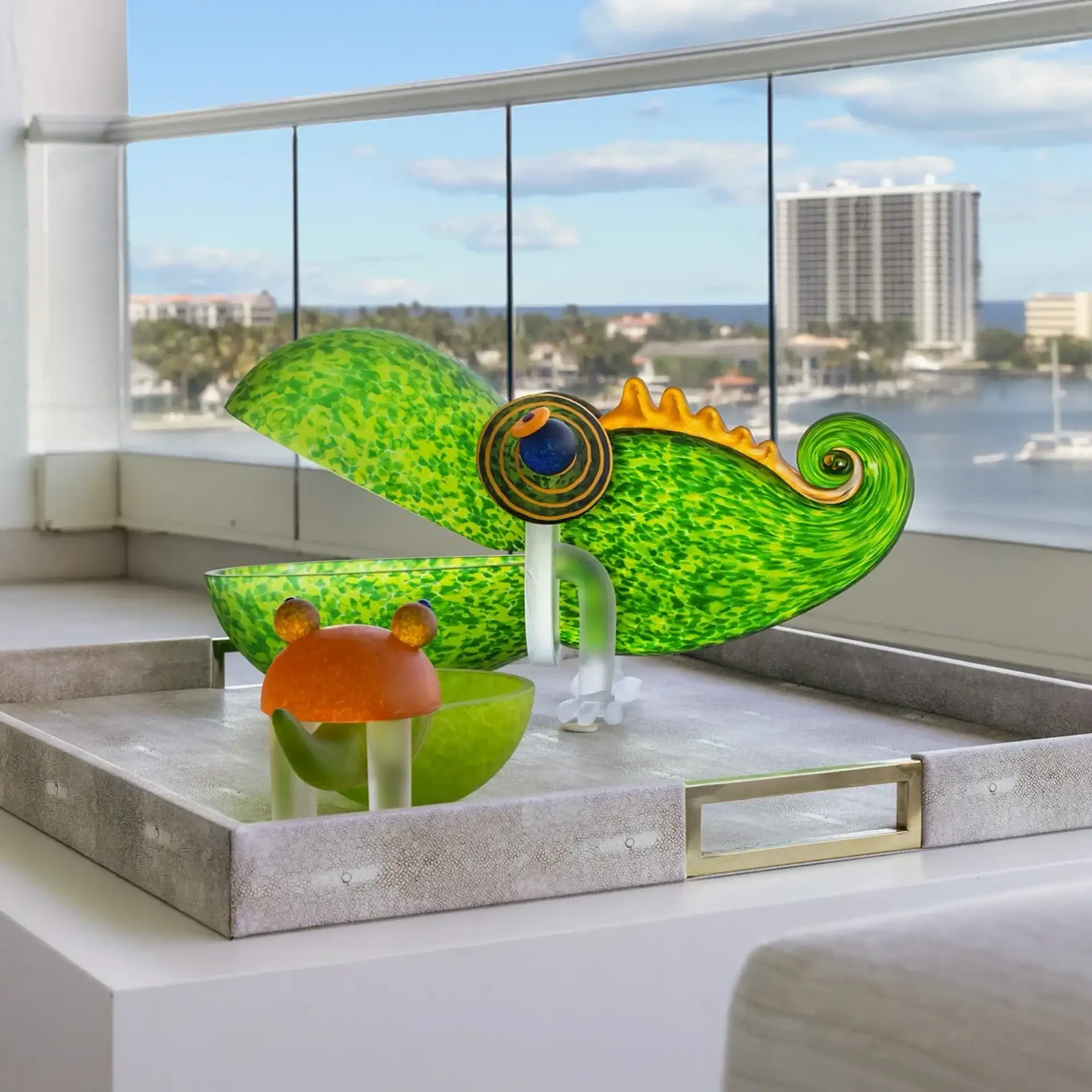 Vibrant green chameleon sculpture with orange and blue accents on a windowsill.