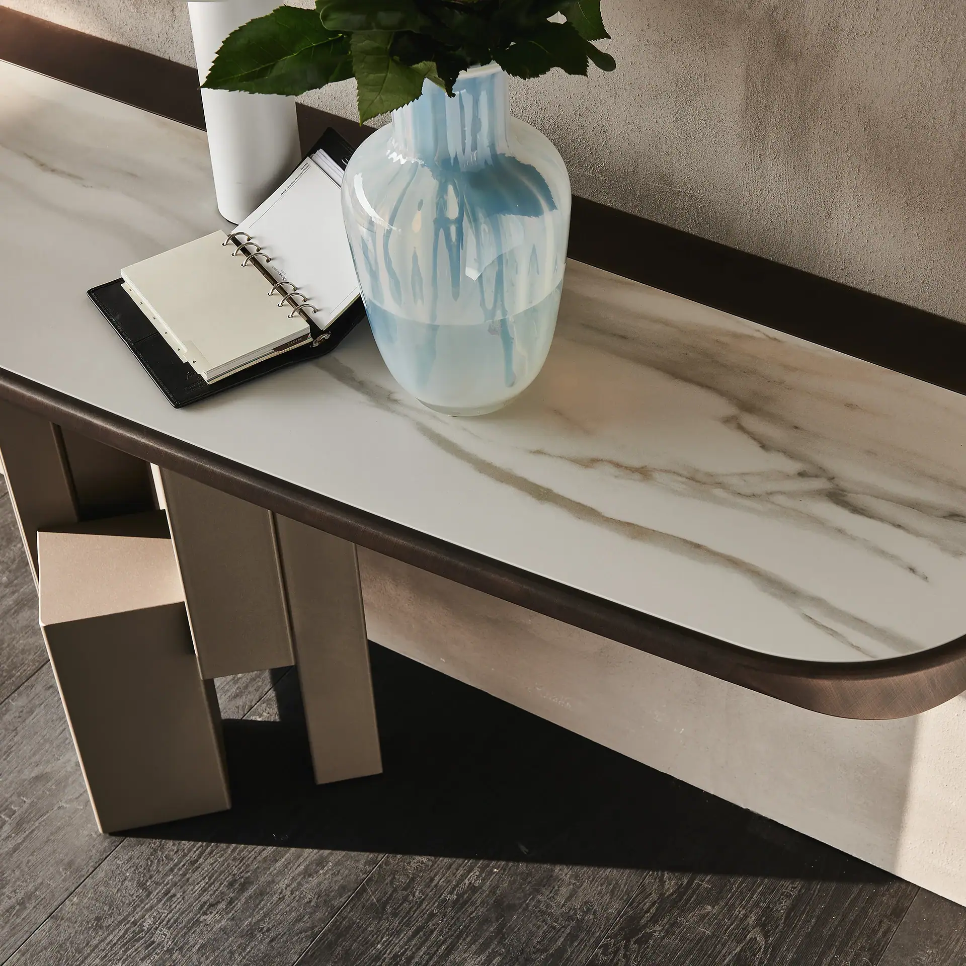 Skyline Console with a blue and white vase and an open notebook on top.
