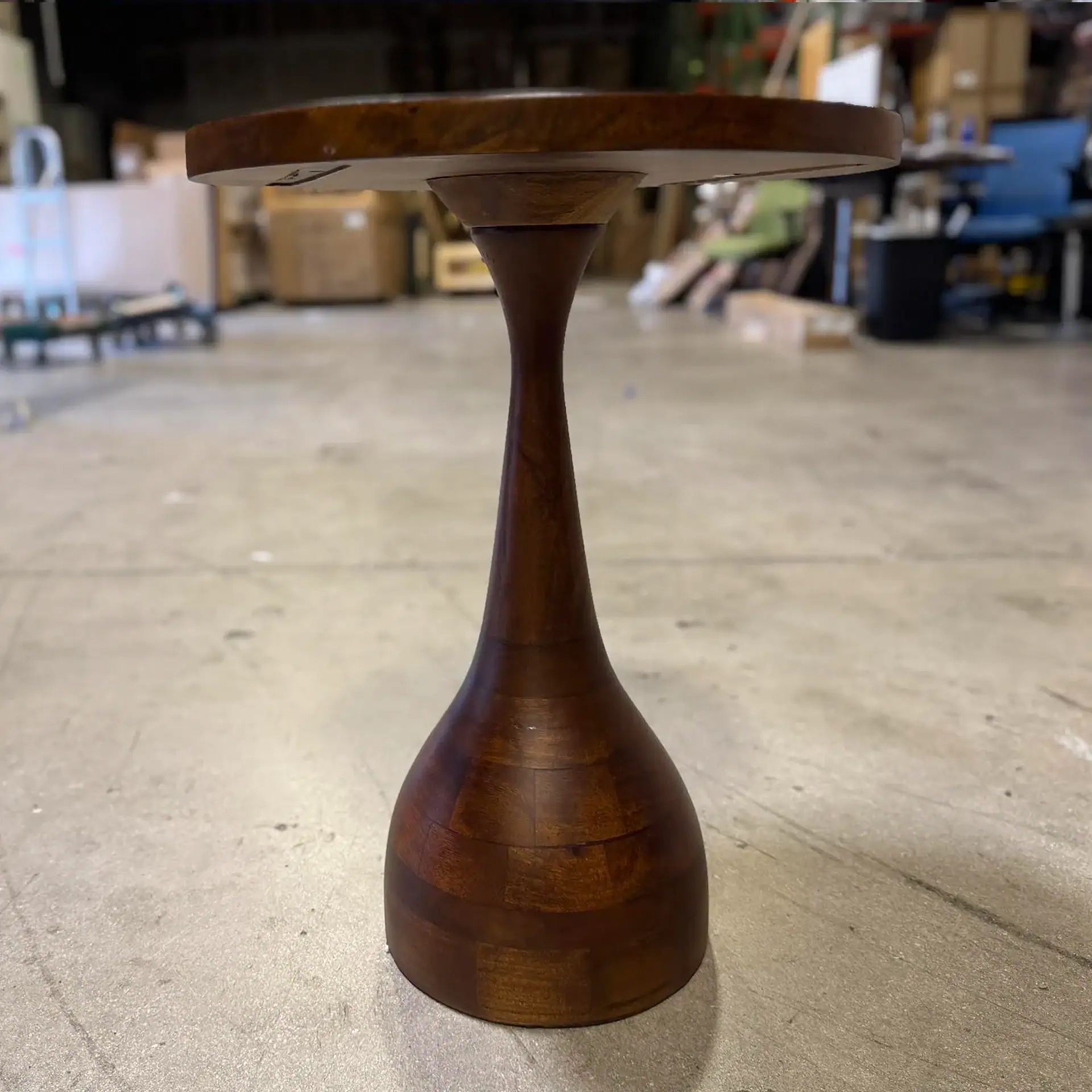 Arteriors Darby Accent Table with wooden finish in a warehouse setting.