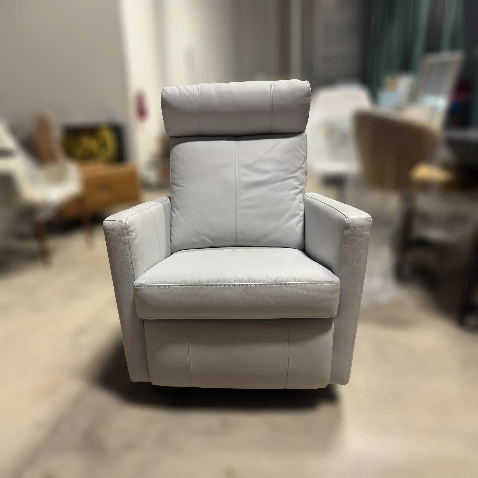 Luonto Track Power Recliner in light grey fabric in a showroom setting.