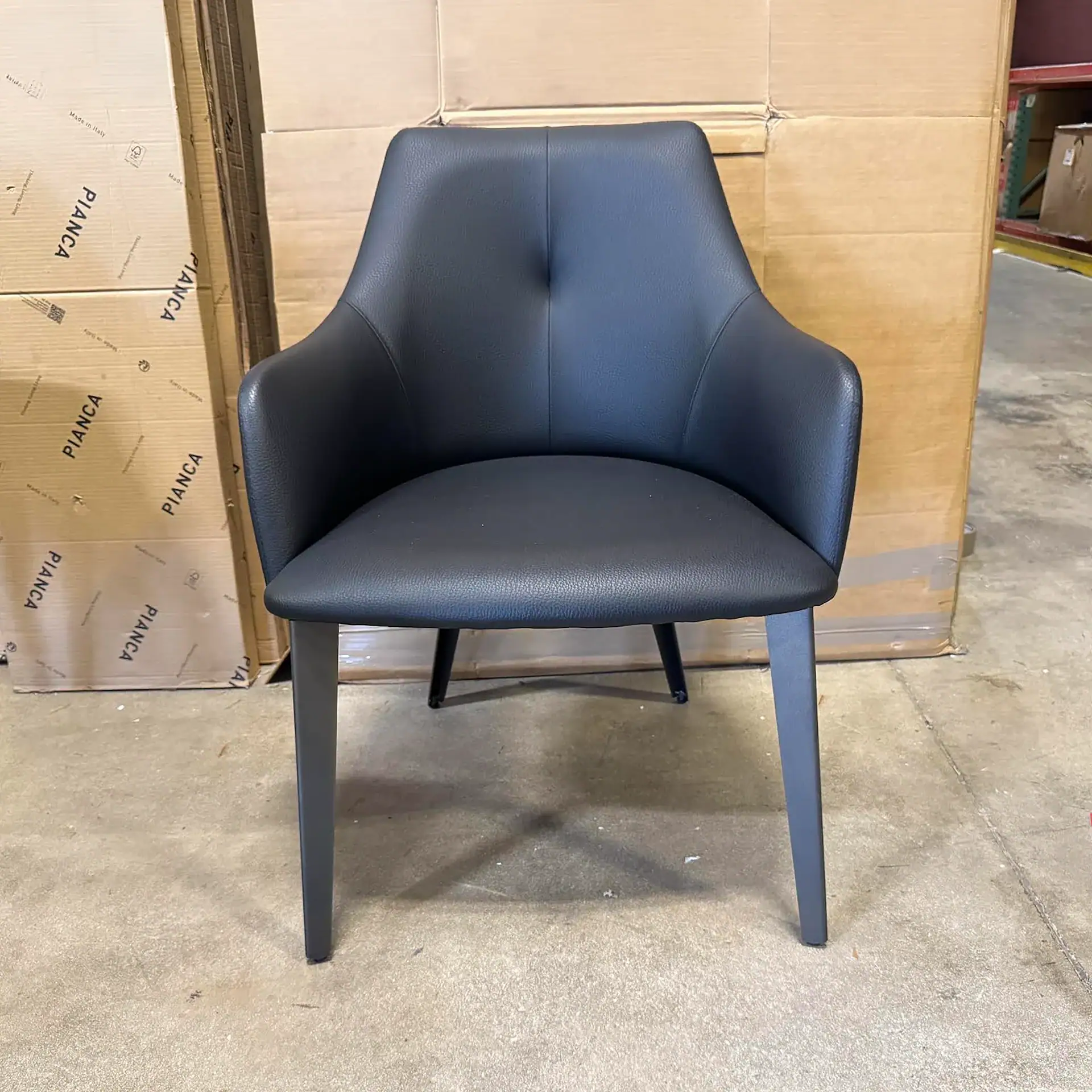Nuevo Renee dining chair in black with wooden legs in warehouse setting.
