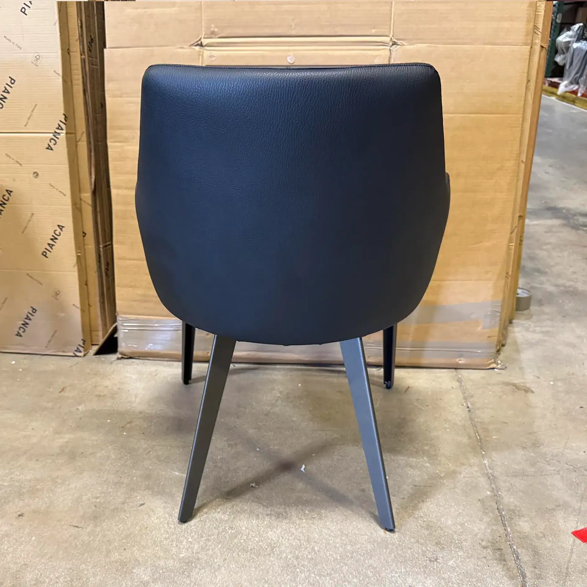 Nuevo Renee dining chair with blue upholstery and black legs in a warehouse setting.