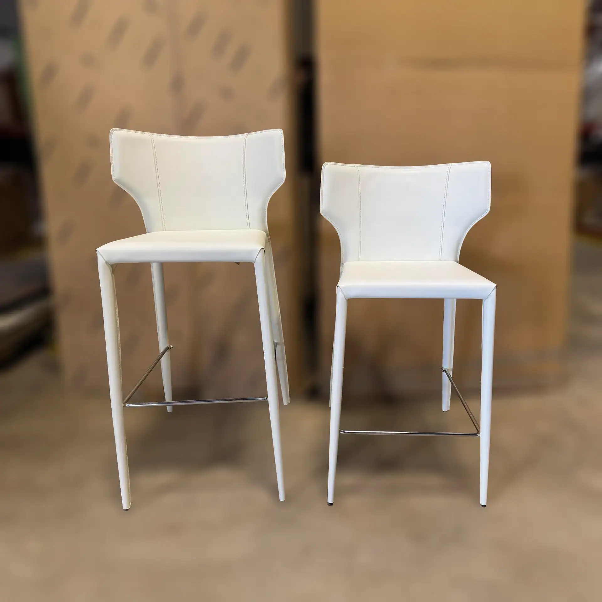 Nuevo Wayne bar stools with white upholstery and high backrests.