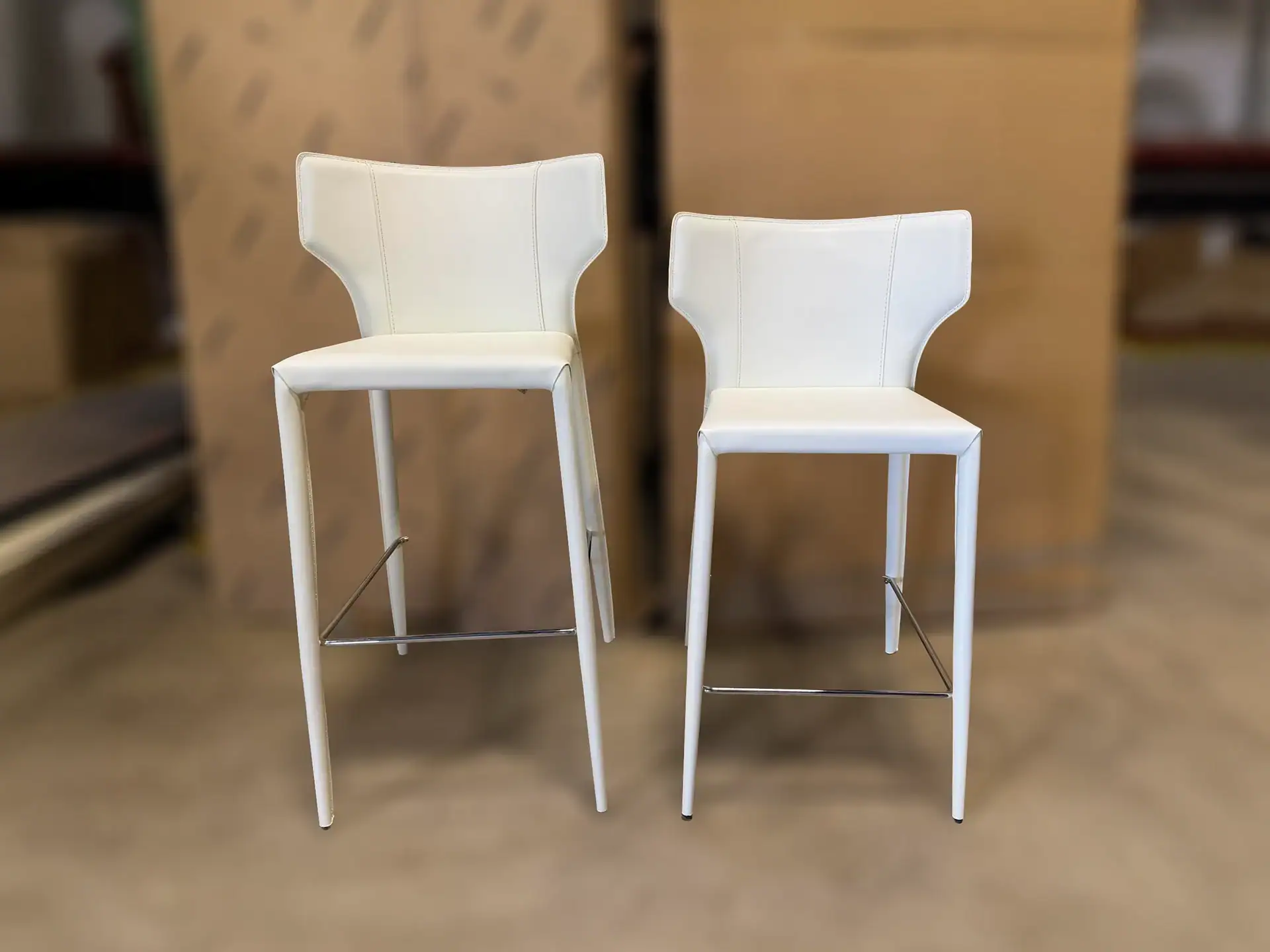 Sklar Furnishings Nuevo Wayne bar stools with white upholstery and metal legs.