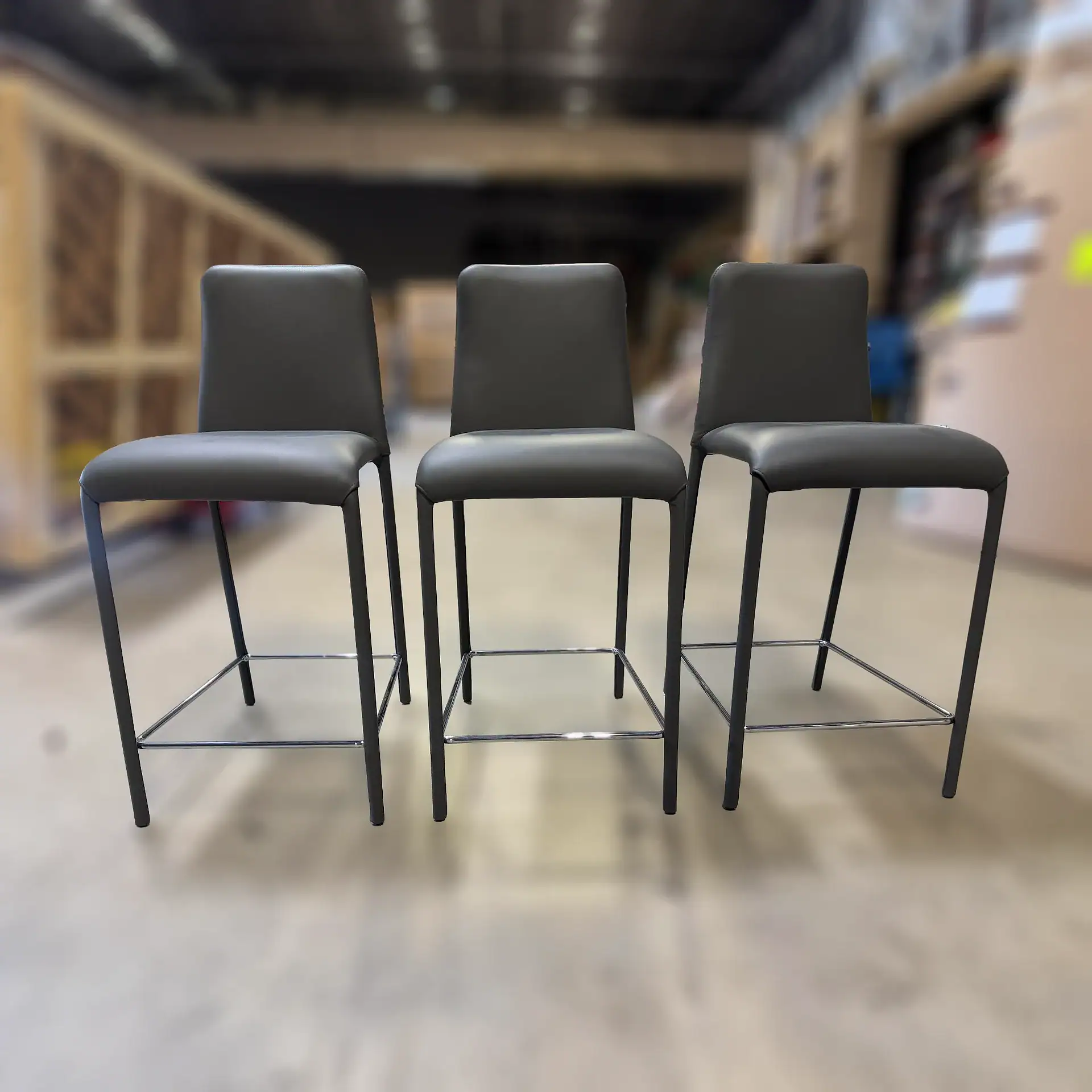 Three Peressini Casa Swing fixed counter stools in a row in a furniture store.