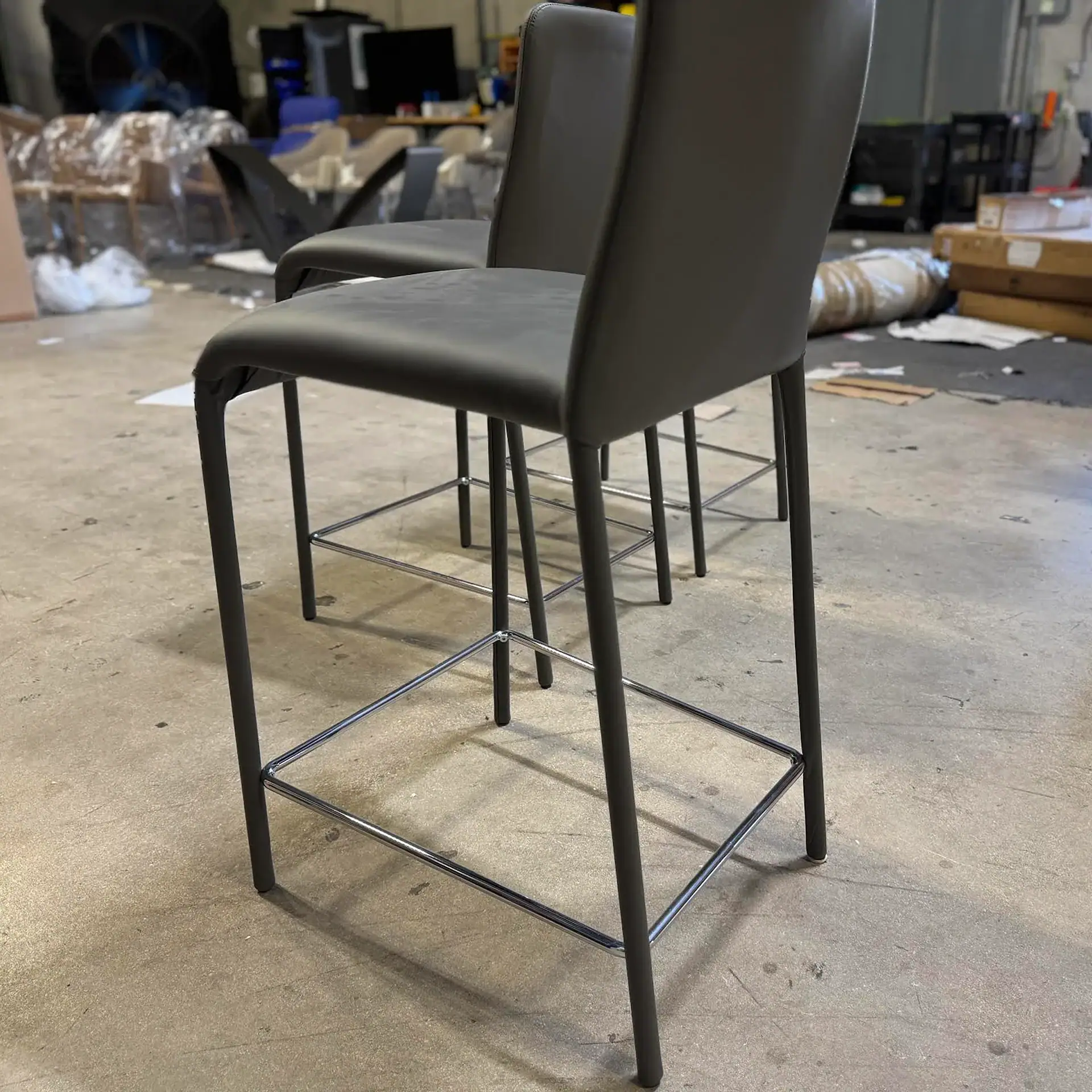 Three grey Peressini Casa Swing fixed counter stools in a warehouse setting.