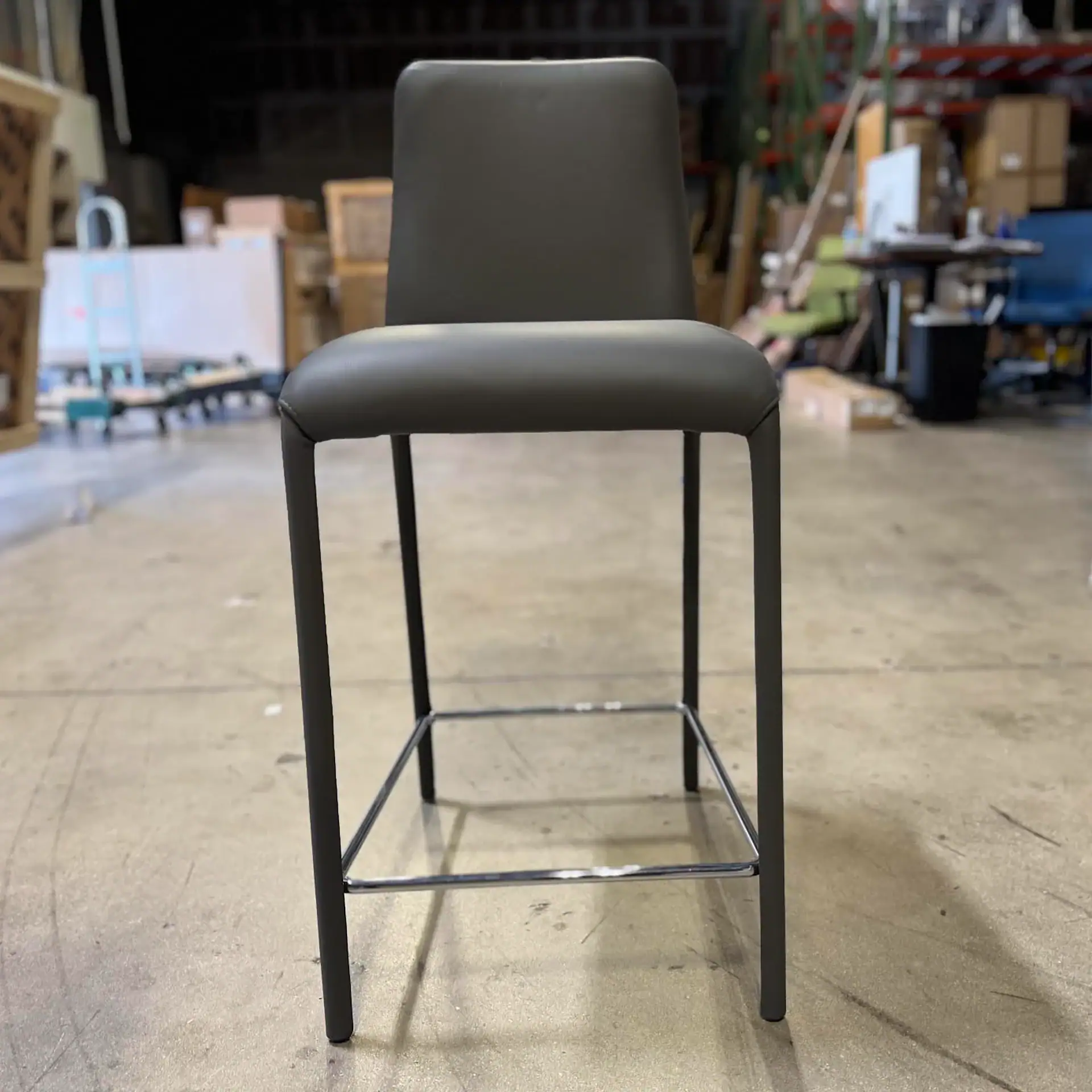 Peressini Casa Swing fixed counter stool with black frame and seat in a warehouse setting.