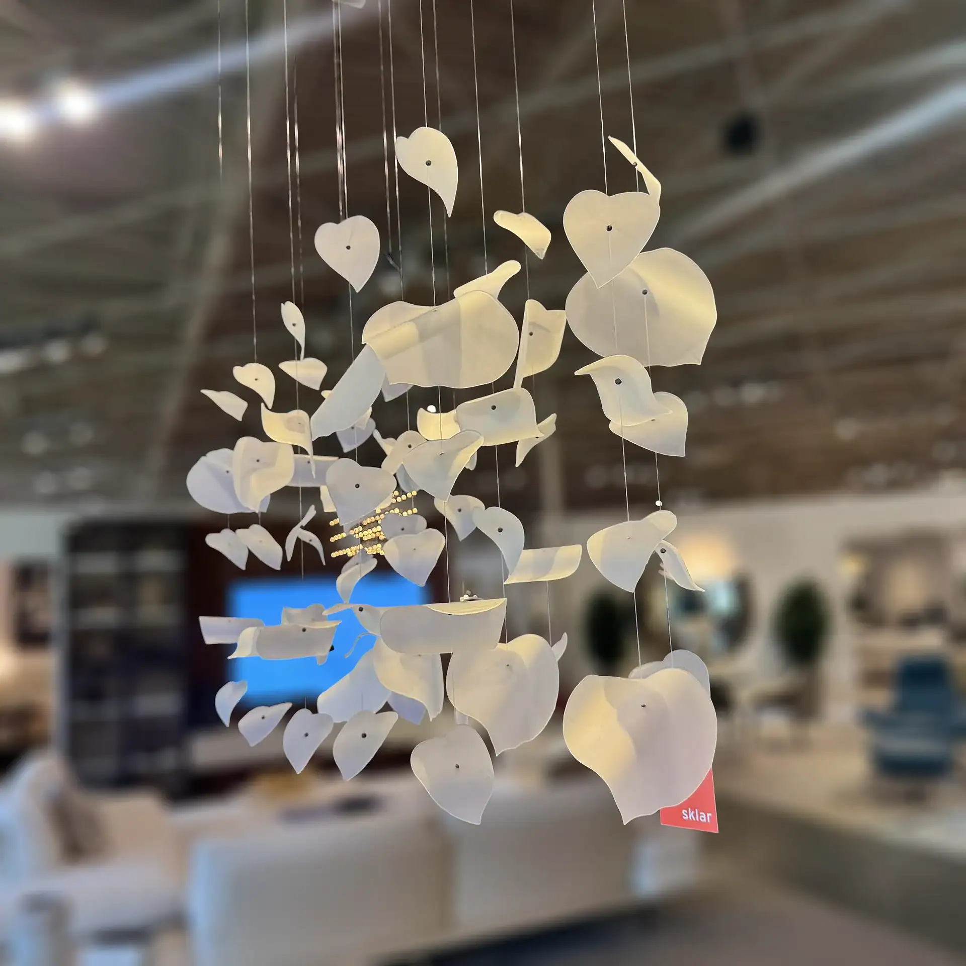 Sklar Furnishings Reflex Leaf LED chandelier hanging in a showroom.
