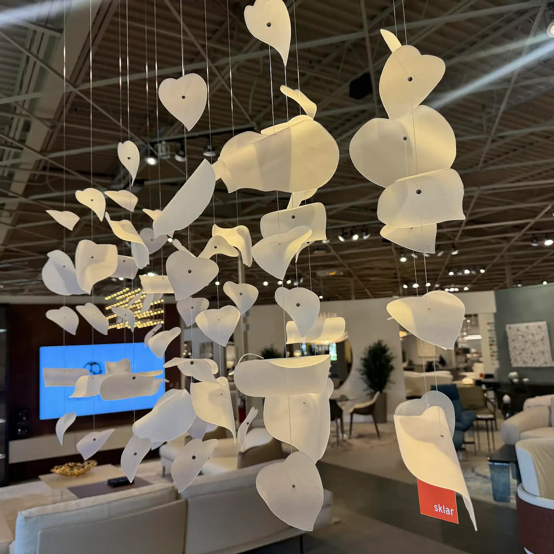 Sklar Furnishings Reflex Leaf LED chandelier hanging in a showroom.