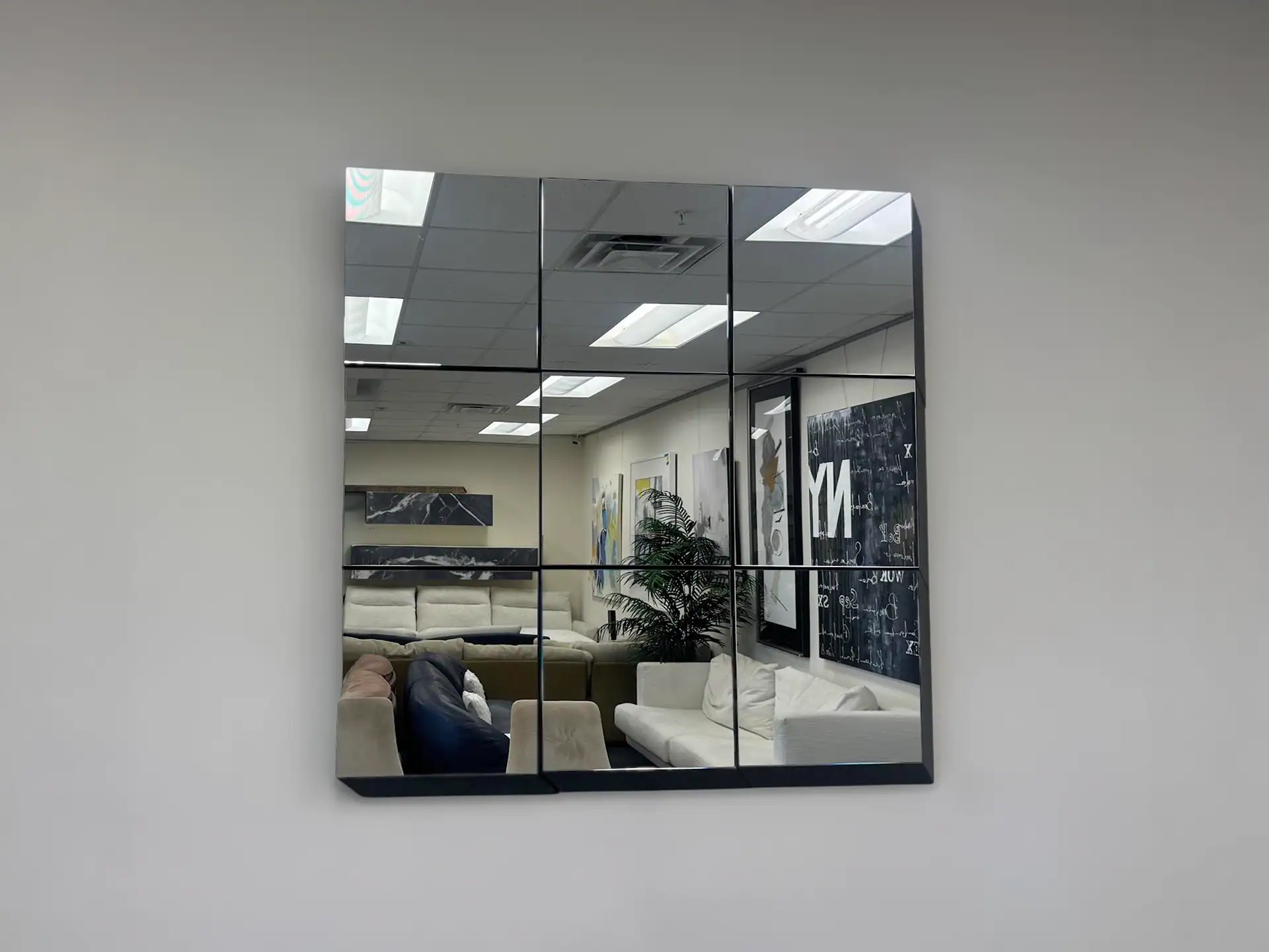 Tonelli Guidoriccio modular mirror tiles on a plain wall in a showroom.