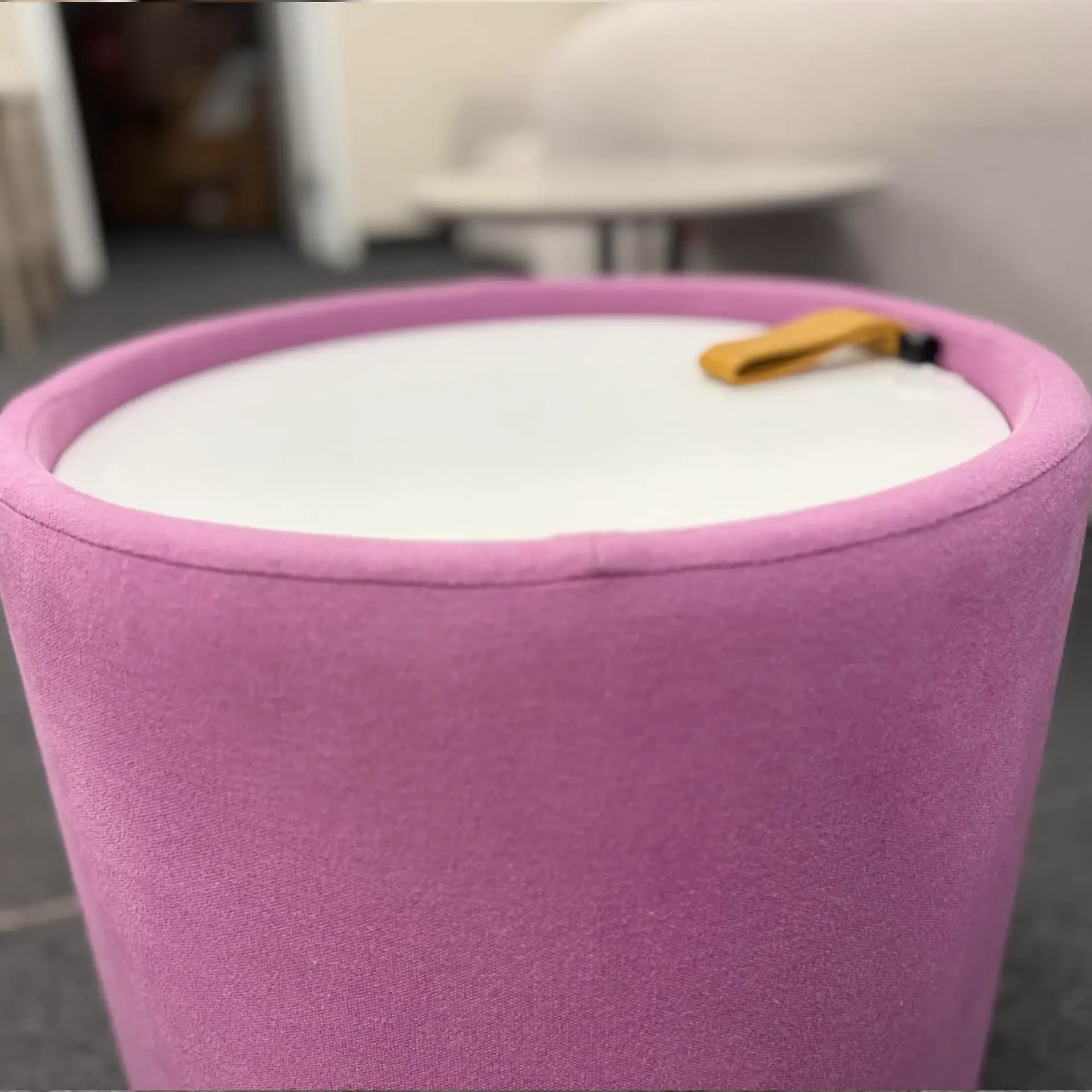 Pink Pill Top Pouf Table with yellow strap on top.