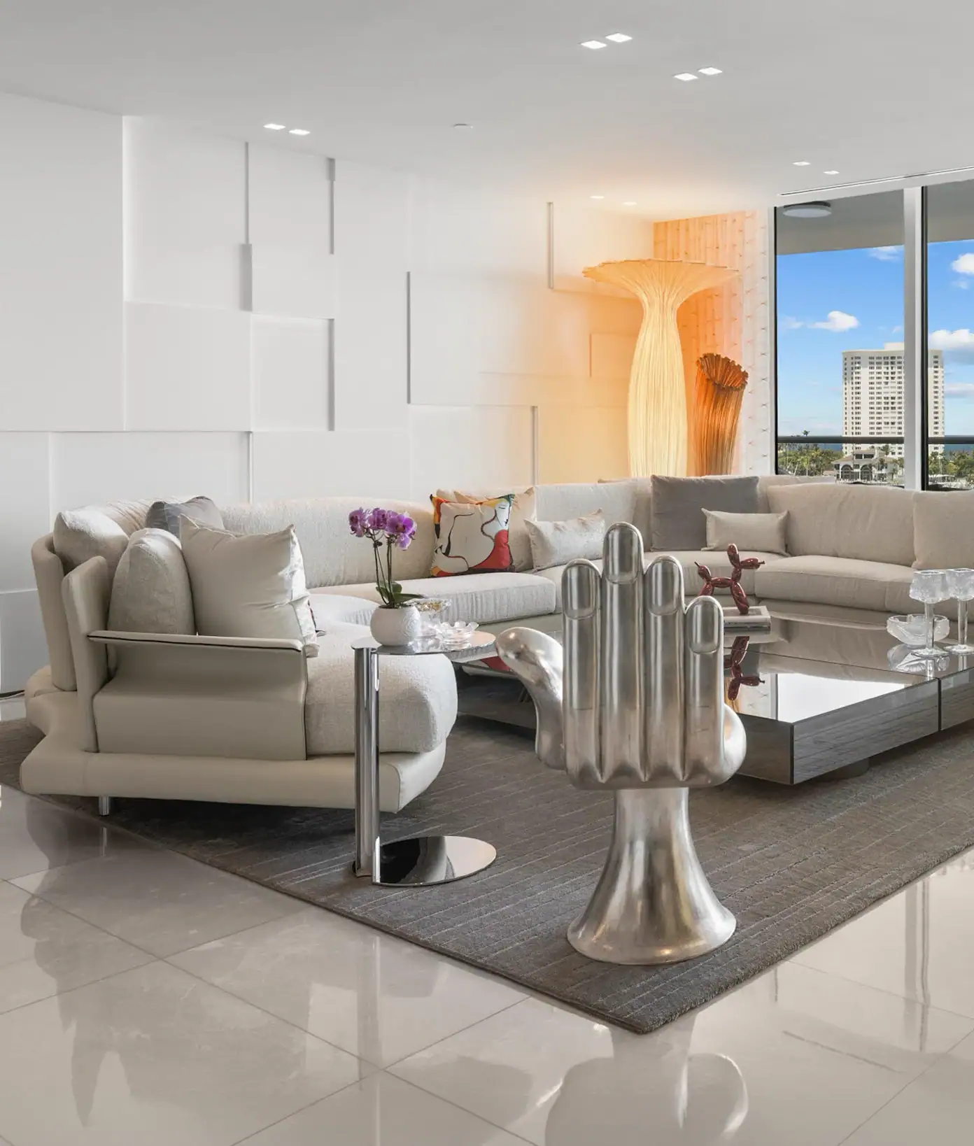 Contemporary living room with white sofas, sculptural decor, and large window view.