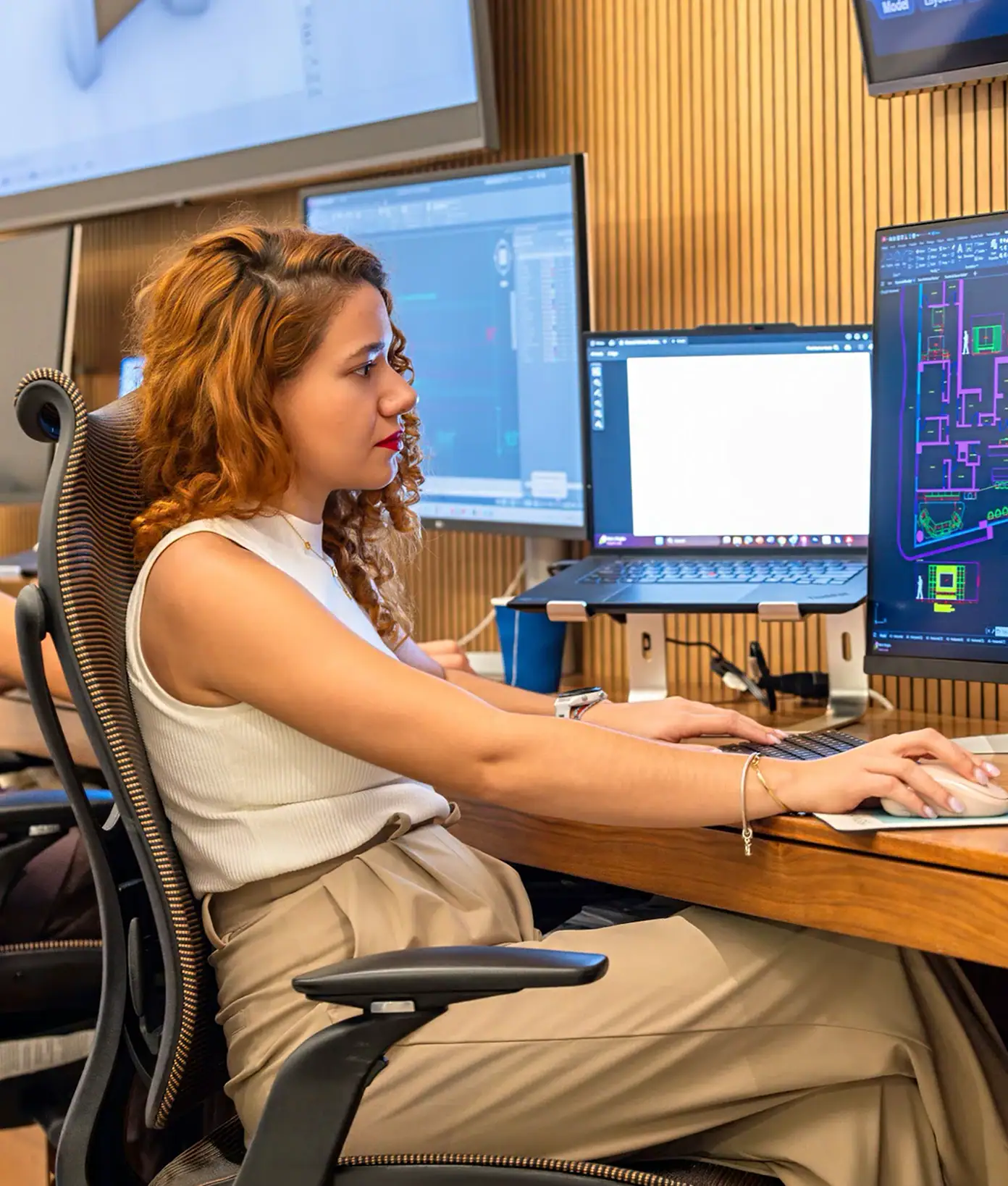 Woman working on digital design at a multi-monitor setup in a modern studio.